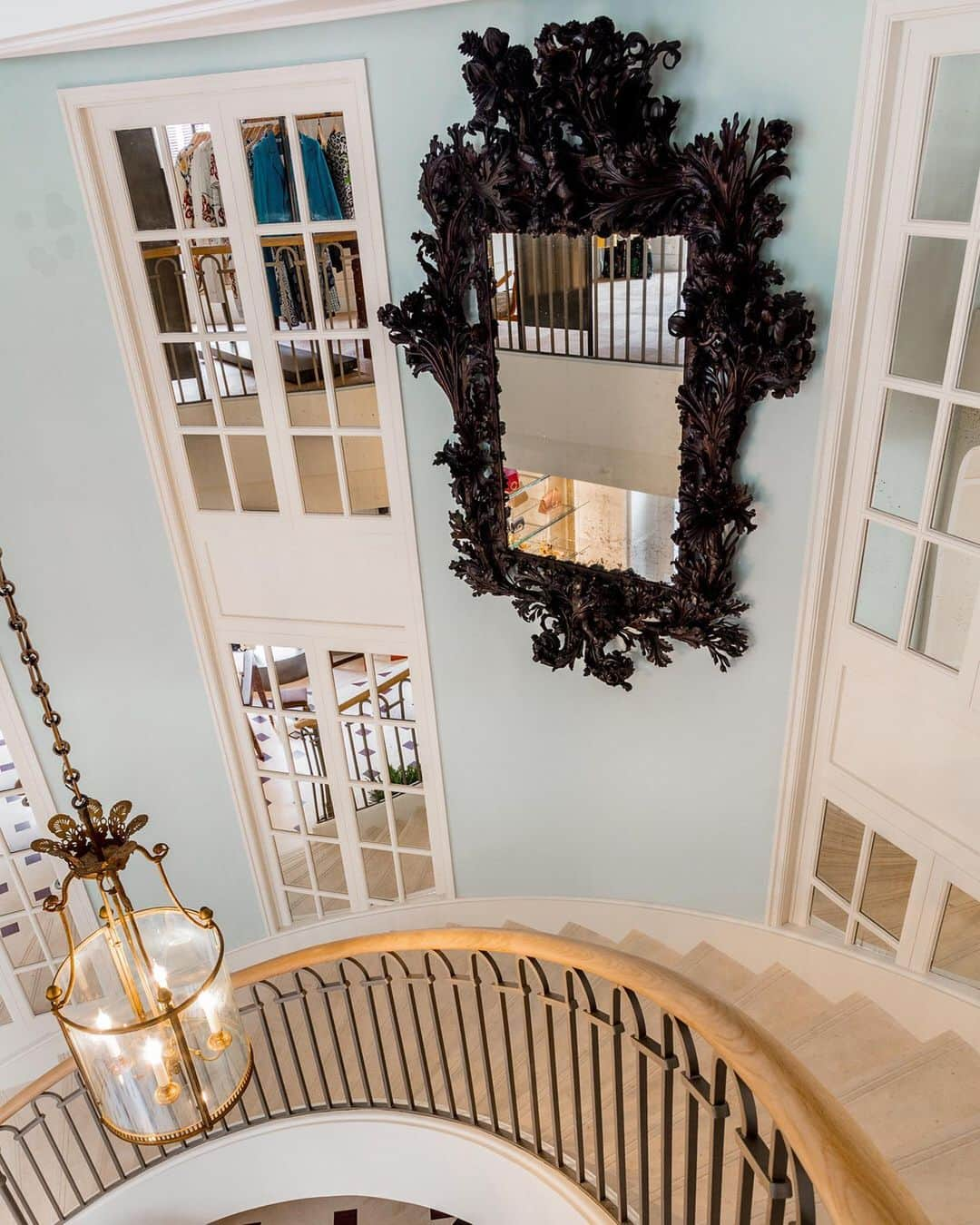 オスカーデラレンタさんのインスタグラム写真 - (オスカーデラレンタInstagram)「A massive Jacobean mirror from Annette de la Renta hangs in the sweeping semicircular staircase across from a ‘30s French Hall Lantern. Swipe to see a Louis XVI-style “voyeuse” chair beside one of a pair of modern neoclassical trellis cabinets which showcase our signature handbags and accessories.」11月21日 5時31分 - oscardelarenta