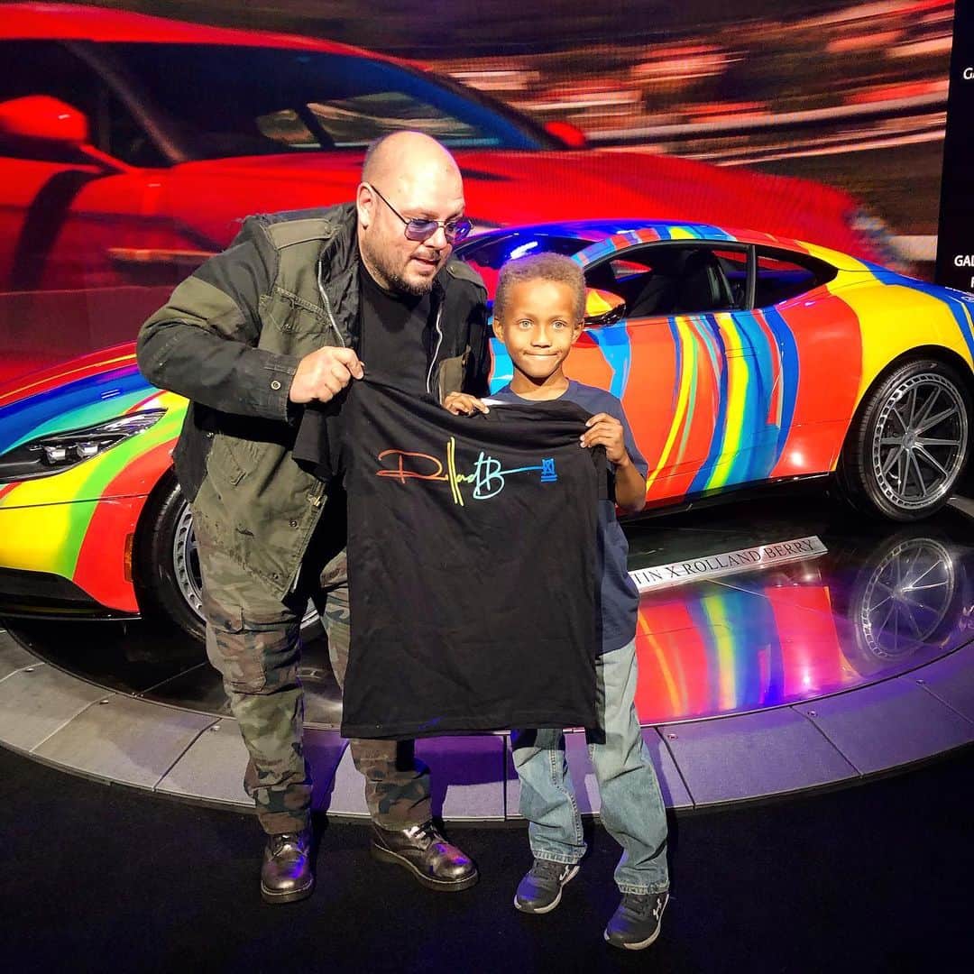 のインスタグラム：「Today @laautoshow good times this little dude was looking at my car like I looked at cars when I was a kid... when I told him I was the artist he was like... NOOOOOOO WAAAAAYYYYY !! I also hand made some tees for the event... he tees cars , mural ... we are DOOOOOOOOING IT!! #rollandberry #astonmartin #laautoshow #galpinautosports #galpin #artcar #believeinyourself #billionaire #buyart #nevergiveup #keepgoing #contemporaryart #streetart #fineart #artofcars #unstoppable #universe #iwillalwaysmissyoujason」