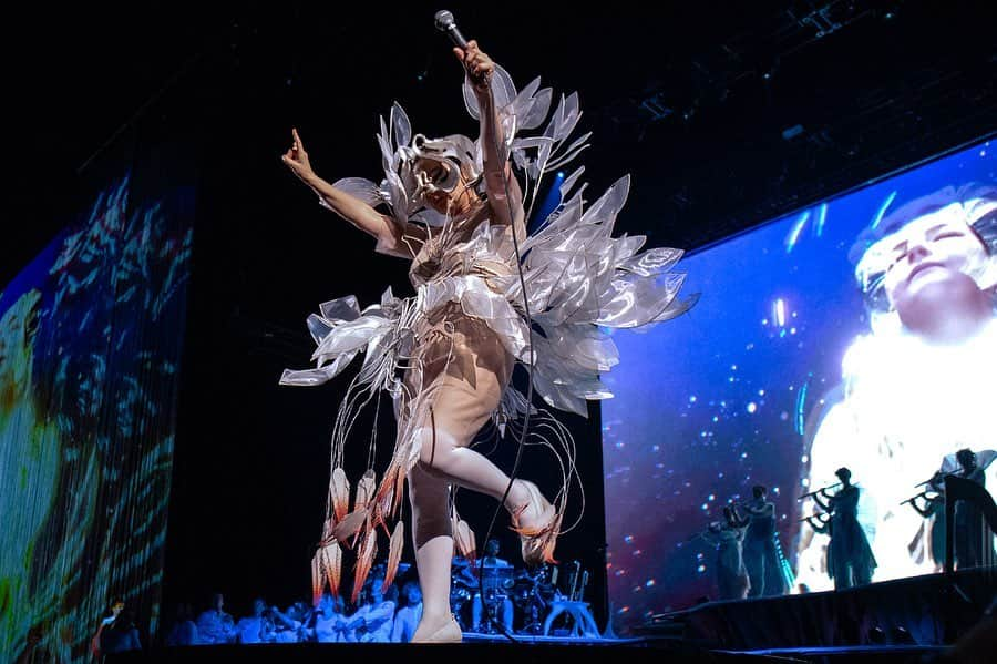 Iris Van Herpeさんのインスタグラム写真 - (Iris Van HerpeInstagram)「Breathtaking @bjork is now stunning Europe with her new multi sensorial 'Cornucopia’ tour, so proud to be part of these revolutionary shows.  The 'Sphaera’ dress is created from transparent organza leaves that are framed in a hybrid material of laser-cut white cotton and mylar, which then are layered sculpturally into a fine frame of water-jet cut stainless steel lines. The leaves are then hand-bent into shape around the body, and can be continuously re-shaped to change silhouette. A fine network of stamen expose outward, finished with handmade feathers of shuiro red and white. The 'Sphaera' dress was inspired by the concept of a living orchid avatar that is layered like an aura around Björk, magnifying her movements.  Mask by @james.t.merry  Photo by @santiagraphy  #irisvanherpen #bjork #sphaera #cornucopia」11月29日 22時19分 - irisvanherpen