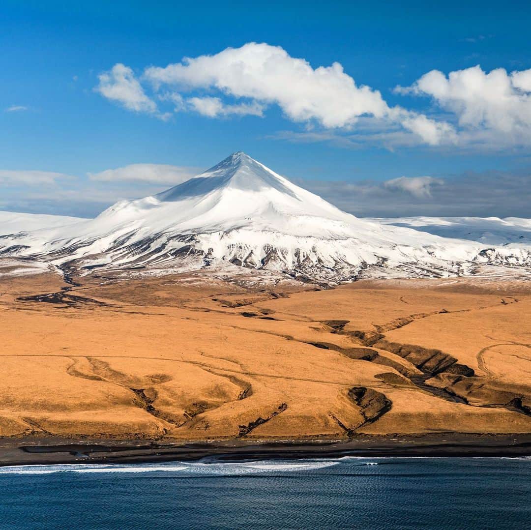 クリス・バーカードのインスタグラム：「Even the harshest environments can at times be peaceful, playful and downright pleasant. It’s these rare slivers of beauty that are so incredibly rewarding to seek out & document. They can feel almost like a gift after being witness to such defeating weather. This moment felt like a distant dream... not a breath of wind, almost surreal. An Aleutian volcano dressed in its spring coating.」