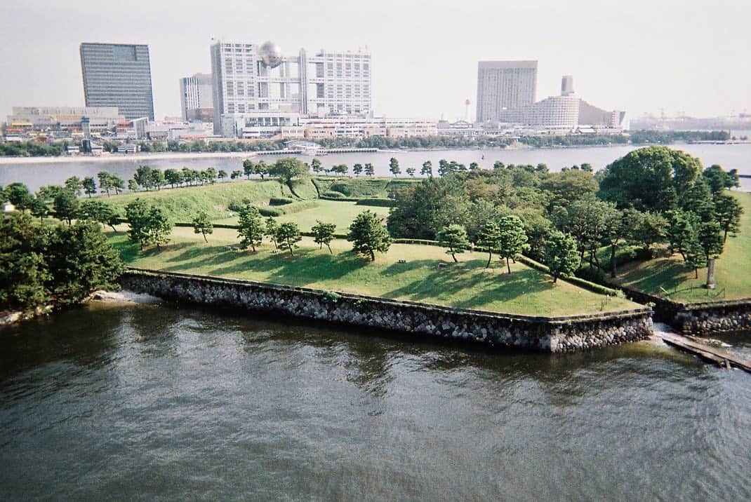 東京DANDYのインスタグラム：「(3/3) This photograph, taken from Rainbow Bridge, is of one of the remaining fortified islands (Daiba No.3) as it is today. It's overshadowed by Odaiba; a massive redevelopment project carried out during the '80s and '90s that created an artificial island in Tokyo bay. The irony is, on that island stands a replica Statue of Liberty (2nd photo, from my archive not in the book). I've selected and sequenced the images in my book to create a narrative between the past and present for future conversations. Odaiba is one of the locations for the Olympics, would you swim in Tokyo Bay? . #DisposablesBook #Disposables #35mm #DisposableCamera #使い捨てカメラ #Tokyo #Japan #Odaiba #AnalogPhotography #Urbex #Island #東京 #日本 #StatueofLiberty #Olympics #Tokyo2020」