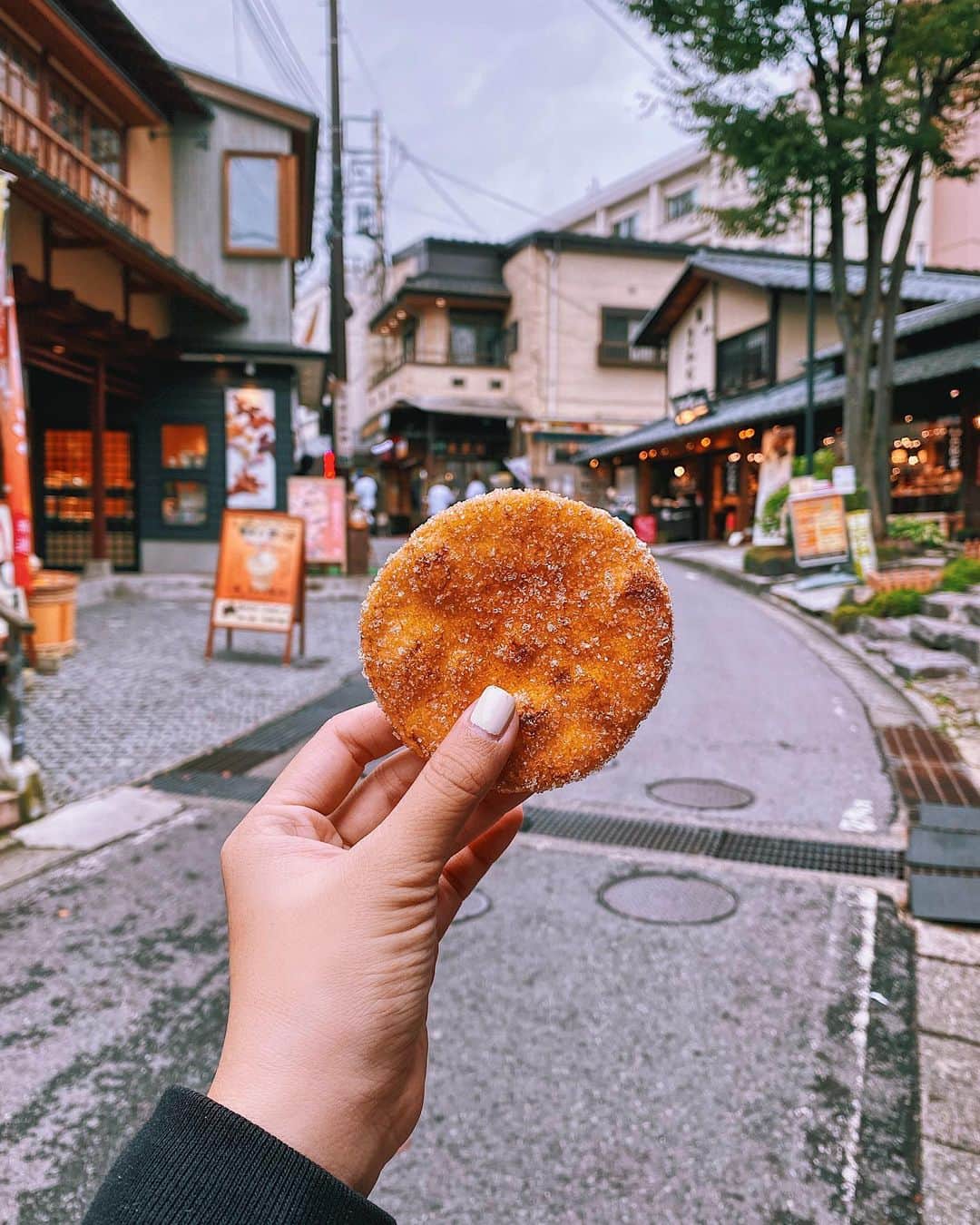 Girleatworldのインスタグラム：「Zarame Senbei (sugared rice crackers) while walking around Kusatsu Onsen town.  Usually senbei is savory with bits of seaweed, but this one is coated with Zarame (large crystal) sugar. It is sweet but still retain that a hint of soy saltiness similar to other senbeis.  Kusatsu is such a charming little town. The entire vibe of the city reminds me of Spirited Away, and it's made extra whimsical on cold nights since the natural hot spring would occasionally stir up steam into the air.  The hot spring water in Kusatsu famous as it is high in acidity and bacterial power, which is believed to be beneficial for skin. Many visitors would dress up in a Yukata (japanese summer wear) ang Geta (wooden slipper) while going to an onsen.  More details on my 5-day Nagano trip is up on my blog! Click the link in my profile ☝🏻 #shotoniphone #shotoniphone11promax #zaramesenbei #senbei #kusatsuonsen #kusatsu  #japan #japanesefood #🇯🇵」