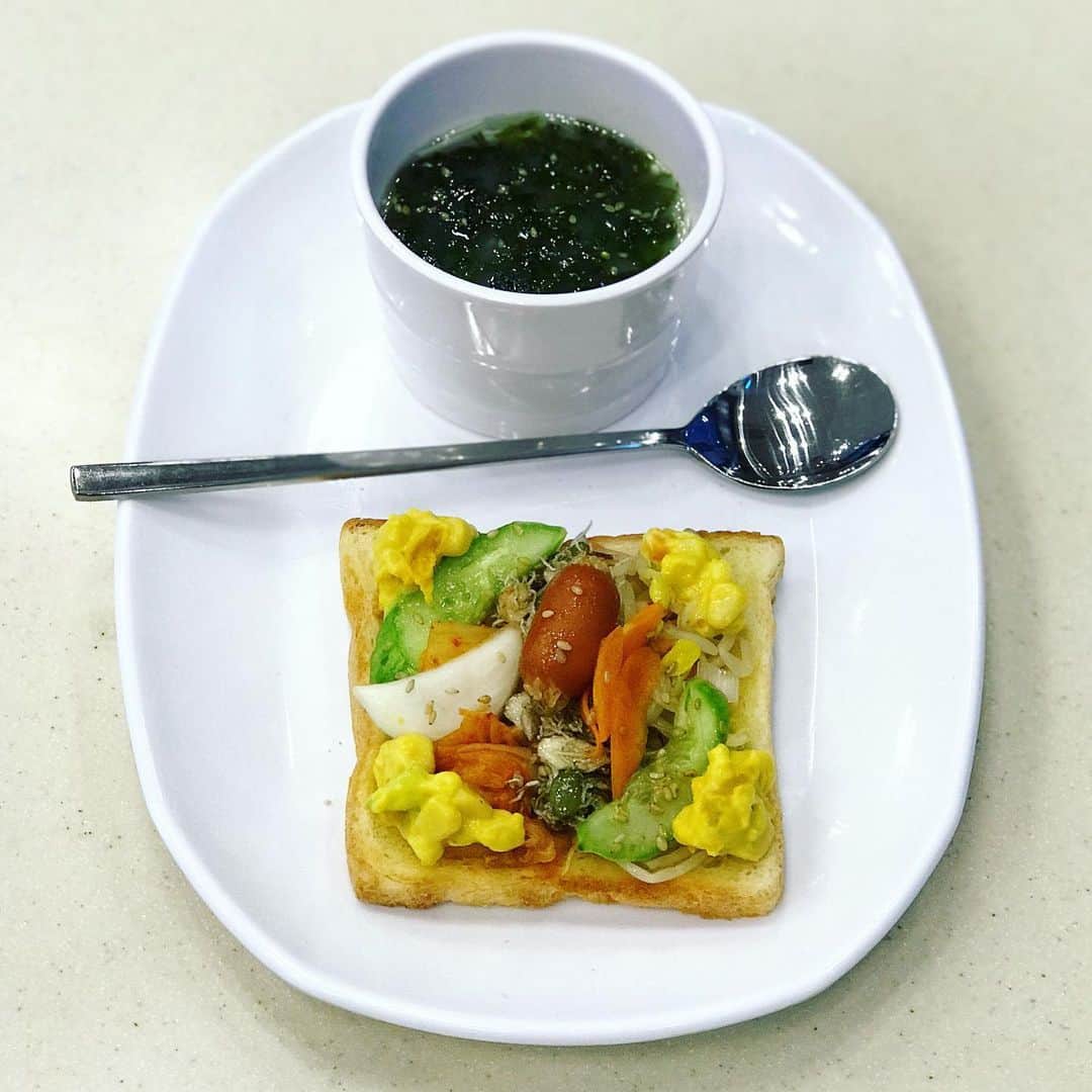 のインスタグラム：「久びさに復活シリーズinソウル #ビジネスホテルのビュッフェでも味はリデザイン出来る。  #ひとり朝食の楽しみ • if you have to eat buffet style breakfast in a common budget hotel, it is possible for you to redesign of a good taste dish. • 【 韓流おかずとキムチの バタートースト・オープンサンド & 韓国海苔の卵スープ】 • ソウルの街は、🍞パン屋さんの オープンラッシュだった。 だからパンに興味があったけど、🌞昼飯、🌚夜飯、📦土産はやっぱりどうしても 韓国🍲料理や🥮菓子を選んでしまいがち。 ホテルのビュッフェは小さな規模でしたが、トースターとバター、韓国のポピュラーな おかずが過不足なくあったし このあと、🥣お粥を食べに行くので パン食にしました。 • 1.  パン食コーナーで、食パン1枚をトングで取り、トースターにセットする。 ・ 2.  韓国おかずコーナーに移動。別の小皿に、胡麻油つきの韓国海苔のフレーク、キムチ、ジャコとかぼちゃの種とアーモンドの佃煮、もやしのナムル、かぼちゃのコーンサラダ、ミニソーセージの胡麻和えを取る。 ・ 3.  トースターがチンと鳴ったら、仕切りのない平皿があったので、それにバターとバターナイフを取り、トーストも載せる。 ・ 4.  席に座る。トーストの両面にナイフで、バターをまんべんなく、薄く塗る。 ・ 5. パンコーナーに戻り、パンを再度トースターで焼く。きつね色にパリッと焼きあがったら、平皿に取る。バターを塗って焼くと食パンの表面がパリパリッとして、汁気を吸いにくいから、サクサクおいしい。 ・ 6. スープコーナーに移動する。カップを平皿に載せ、卵スープを注ぐ。スプーンと箸を取る。 ・ 7.  席に座る。バタートーストに箸でキムチ、ジャコ、ナムルを並べて載せる。その上にソーセージを載せ、四隅にかぼちゃのコーンサラダを載せる。 ・ 8. 卵スープに韓国海苔フレークをたっぷり加え、スプーンを添える。小皿と箸を片付けたら、いただきます。 ・ 9. 食器を片付けたら、平皿を取り、ドリンクコーナーで、あまりにかわいい紙コップにオレンジジュースを注ぐ。コーヒーベンダーでカフェオレを注ぐ。 ・ 10.  席に座る。デザートものが全くないバイキングだったので、紙コップのかわいさを愛でつつ、しばしくつろぐ。 ・ もちろんおいしい。 ・ #ソウルの朝ごはん #myown #indevidualbreakfast」