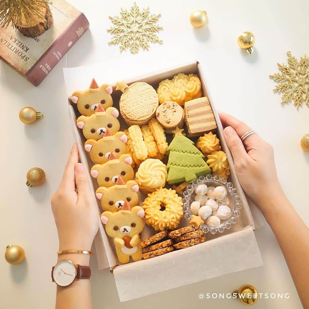 Song Sweet Songのインスタグラム：「🍪🐻🎁✨ . クリスマス🎄クッキーはいかがですか〜✨ 。 Christmas is coming and my assorted cookie is ready 🎄✨ 。 ของขวัญสุดฮิตช่วงนี้ ต้องหนีไม่พ้นคุกกี้แน่นอนค่ะ สองทำกล่องนี้เป็นไอเดียน่ารักๆ เผื่อใครยังนึกไม่ออกว่าจะให้อะไรเป็นของขวัญปีใหม่  ลองเอาคุกกี้หลายๆรสมาจัดเรียงในกล่องแบบนี้ดู ใครที่ได้รับไปแล้ว เปิดมาเจอแบบนี้ต้องร้องว้าวแน่ๆฮะ~🎄✨ #rillakuma #リラックマ　#アイシングクッキー　#クッキー　#christmas  #christmasgifts  #christmasgiftideas  #foodphotography #foodblogger #xmas #xmas2019  #cookiedecorating  #icingcookies  #decoratedcookies  #royalicingcookies  #cookiestagram #냠냠  #맛스타그램  #크리스마스  #크리스마스선물  #おうちカフェ  #手作りお菓子 #bakedwithlove #songsweetsong  #songsweetsong_cookie_diary #songsweetsong_iceboxcookies . 。 。 . 。 。 . Gifts of time and love are surely the basic ingredients of a happy holiday! ❤ . … 。。 ส่งท้ายปลายปีด้วยโปรโมชั่นจาก @danielwellington และรับส่วนลดถึง 20% เมื่อซื้อสินค้าสองชิ้นหรือสองชิ้นขึ้นไปเฉพาะที่ www.danielwellington.com! และอย่าลืมใช้โค้ด sweetsong2019 รับส่วนลดเพิ่มอีกทันที 15% เพื่อประหยัดสูงสุดถึง 32%. ทุกออเดอร์มาพร้อมกับบริการห่อของขวัญ! #DanielWellington #DWThailand #DWinTH」