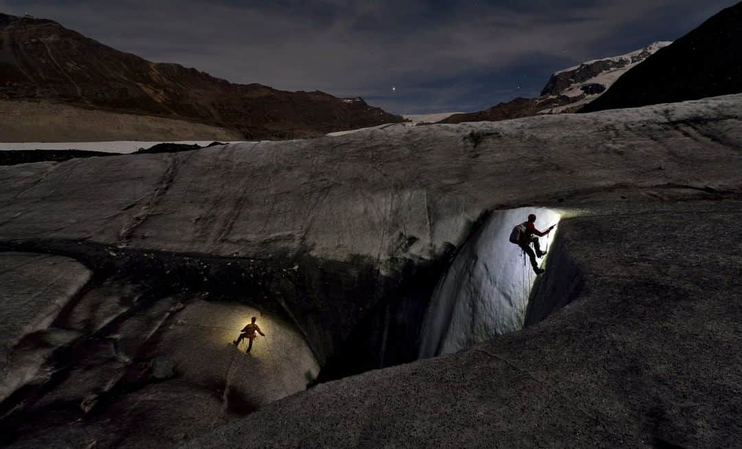 National Geographic Travelさんのインスタグラム写真 - (National Geographic TravelInstagram)「Photo by Robbie Shone @shonephoto | Two cavers return to the surface after exploring this giant moulin on the Gorner Glacier in Switzerland. The temperatures are much colder during the evening than during the day, which reduces the risk of the flowing meltwater that makes these moulins so dangerous.」12月23日 6時05分 - natgeotravel