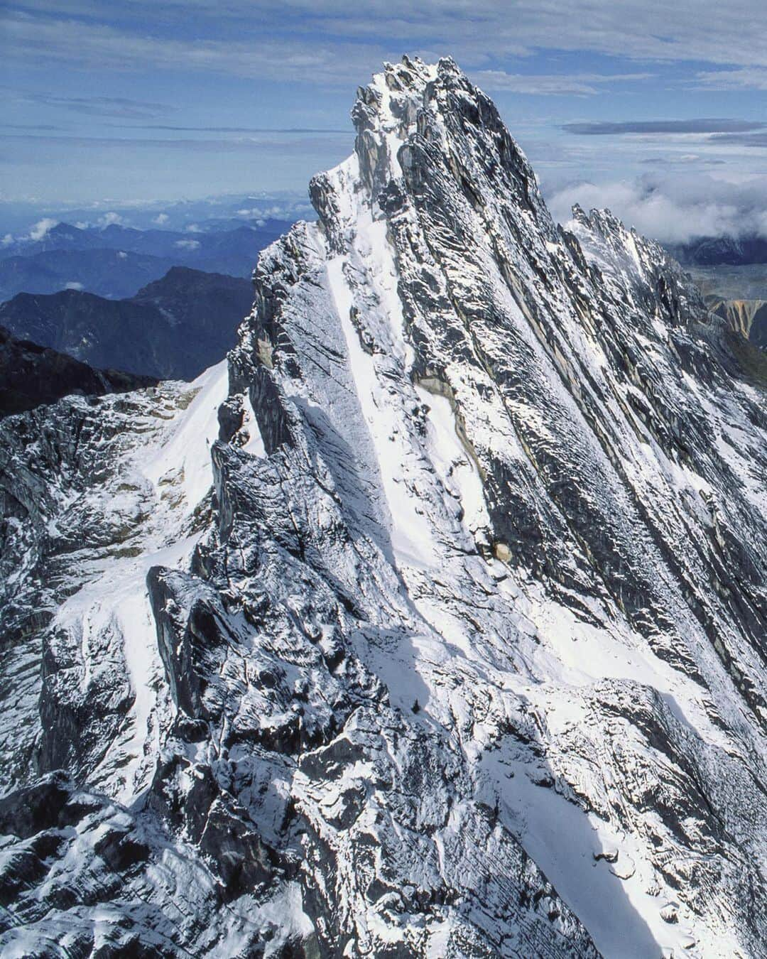 ナショナルジオグラフィックさんのインスタグラム写真 - (ナショナルジオグラフィックInstagram)「Photo by George Steinmetz @geosteinmetz | A rare helicopter view of Puncak Jaya, the highest point (16,024 feet) on the greater Australian continent. It’s the spine of New Guinea—and a great example of the force of continental collision. The peak is awkward to access, as it’s adjacent to the world’s largest gold and copper mine, Grasberg (at right), the source of great wealth for some and of conflict for the locals. This view is from 1993, when I spent a year in Irian Jaya (now West Papua) on assignment for @natgeo. It took a lot of convincing mine management to get my butt on that chopper. #sevensummits #carstenszpyramid  To explore more of our world from above, follow @geosteinmetz.」12月24日 0時38分 - natgeo