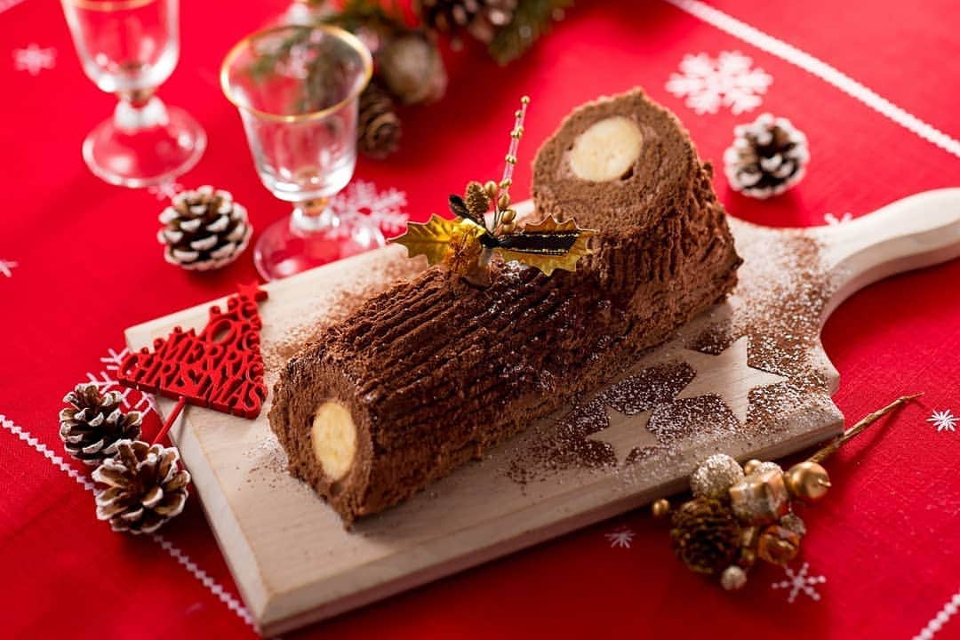Dole_jp ドール ジャパンのインスタグラム：「バナナブッシュドノエル🍌🎄 ． バナナを使ったDOLE流のブッシュドノエルでクリスマスに華やぎを✨😆 . . 📓材料（8人分） . ・バナナ ２本🍌 . ＊スポンジ生地（28㎝×28㎝） ・卵 ３個🥚 ・グラニュー糖 60ｇ ・薄力粉 50ｇ ・ココアパウダー 10ｇ ・牛乳 20ｇ ・サラダ油 大さじ１ . ＊チョコレートクリーム ・生クリーム 200ml🐮 ・チョコレート 100ｇ . ＊飾り用 ・ココアパウダー 適量 ・粉砂糖 適量 . . 📓作り方 . ①下準備とスポンジ作り🙌 ✳️薄力粉とココアパウダーは合わせてふるっておく ✳️牛乳とサラダ油は合わせてひと肌程度に温める ✳️ボウルに卵を割り入れ、湯煎にかけながらハンドミキサーで混ぜる ✳️途中、グラニュー糖を３回程度に分けて加え、まったりとするまで泡立てる ✳️ふるった粉類を加えて粉っぽさがなくなるまでさらに混ぜ、牛乳とサラダ油も加えて、サッと混ぜる ✳️わら半紙を敷いた天板に流し28㎝×28㎝にならす ✳️200℃に予熱しておいたオーブンで12分焼き、焼き上がったら網の上で冷ます。 . ②チョコレートクリームの準備🍫 ✳️チョコレートを砕いてボウルに入れ、湯煎にかけて溶かす ✳️分量の生クリームを少し加えてのばしてから残りの生クリームのボウルに入れる ✳️チョコレートとクリームが完全に混ざったら、氷水にあてながら八分立てにする。 . ③デコレーション😆 ✳️スポンジ生地の巻き終わりになる端を少し斜めに落とす ✳️チョコレートクリームの半量を全面に塗る ✳️手前にバナナを並べ、端からくるりと巻き、巻き終わりを下にしてなじませる ✳️ロールケーキの左側を６㎝ほど斜めに切って切り株に見立て、右端にのせてくっつける ✳️残りのチョコレートクリームを切り口を除いて全面に塗り、フォークで丸太状に模様をつけ、ココアパウダーと粉砂糖でデコレーションする . . . #ドール #Dole #ブッシュドノエル #バナナ #チョコレート #チョコクリーム #クリスマスレシピ #レシピ #おうちcafe #banana #cooking #recipe #Delistgrammer #デリスタグラマー #instafood #インスタフード #デリミア #クッキングラム #foodart #デザート #スイーツ部 #クリスマスパーティー #クリスマス準備 #christmas #xmas #party #buchedenoel」