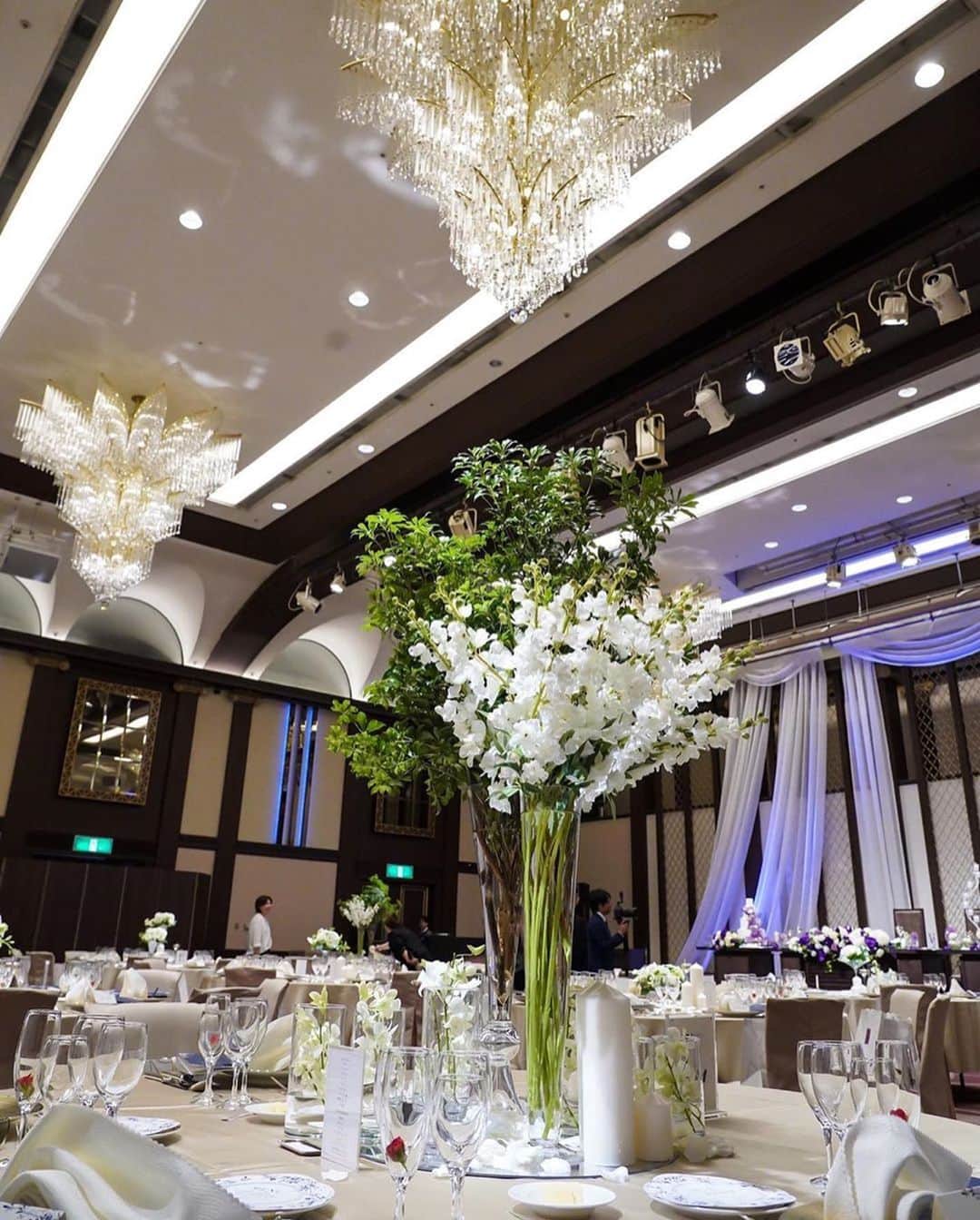 ゼクシィさんのインスタグラム写真 - (ゼクシィInstagram)「【洗練された大人の会場コーディネート💜】 . 今回は、#ゼクシィ2019 のハッシュタグをつけて 投稿頂いた中から、大人の会場コーデ実例をご紹介します😊✨ 白とグリーンで統一されたテーブル装花は 背の高い花器で高さを出して☺️ ボリュームを上に持ってくることで生まれた天井の高さや ゴージャスなシャンデリアとのバランスが絶妙👏💕 . ウエディングケーキも高さのあるシンプルな4段🎂 会場の白に映えるパープルのフラワーが主役感たっぷり💐💜 . シンプルながらも計算しつくされた大人のコーディネート、 洗練された美しさを目指すならぜひ参考にして😌⭐️ . @ponriara さま . . +♥+:;;;:+♥+:;;;:+♥+:;;;:+♥+:;;;:+♥+:;;;:+♥ . プロポーズから結婚式まで素敵なお写真募集中！ . ゼクシィ公式アカウントでお写真を紹介してみませんか？ 【#ゼクシィ2019】 を付けて投稿してください📷💎 . +♥+:;;;:+♥+:;;;:+♥+:;;;:+♥+:;;;:+♥+:;;;:+♥ . ▼花嫁さんダウンロード数No.1 ゼクシィアプリはURLから🕊🍃 @zexyrecruit . . #ウェディングケーキ#ケーキ入刀#ケーキトッパー#ケーキ装花#ウェディングケーキデザイン _ #ファーストバイト#サンクスバイト#ケーキカット#ケーキ#会場装花#テーブル装花#ウェディングフォト#卒花#卒花嫁 _ #2019冬婚#2020秋婚#2020夏婚#2020春婚#結婚準備#結婚式準備#全国のプレ花嫁さんと繋がりたい#日本中のプレ花嫁さんと繋がりたい#ゲストテーブル#ネイキッドケーキ _ #阪急インターナショナル#ゼクシィ#ちーむゼクシィ#プロポーズされたらゼクシィ」12月25日 11時50分 - zexyrecruit