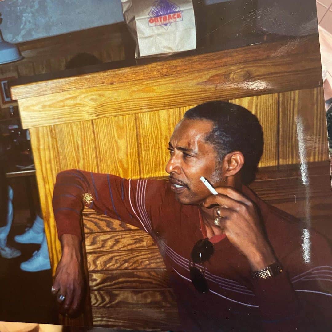 ケリー・ヒルソンのインスタグラム：「Looking through old pics has evoked the brightest smile my face could muster over these past few days. Though I don’t believe I’d ever seen this one before, it captures the essence of Dad so accurately it astounds me...THIS is the man my heart sees from childhood (he got sillier the older he got, lol)...Ray-Bans hanging from his collar, the rings, the watch, the cig, that brow furl, the stern expression that could birth his charming grin right behind it, the side-burns, the greys we gave him, and don’t forget the signature cool ass elbow placement. He was always leanin’. And get this—the bag reads “Outback Steakhouse.” That was his birthday request every year (the lamb-chops), with only a few exceptions. My last post actually included a vid of him enjoying his very last birthday song there. I’m actually smiling right now. Wow.」