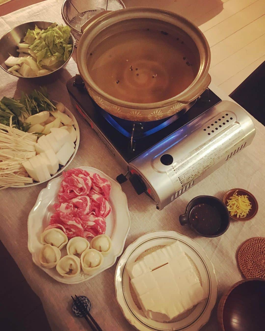 のインスタグラム：「夕方からぐんと冷えたので、今夜はお鍋♨️ 牡蠣出汁ベースのスープに台湾のマーガオをたっぷり入れてスタンバイ。  上等のきぬ豆腐に、邦栄堂の皮で仕込んだストック冷凍水餃子に豚の肩ロース。お野菜はお正月の残り物の水菜に白菜、大根、ねぎ、えのき茸。そして欠かせないのが越中葛きり。  たれはあご出汁とお醤油、黒酢とレモン、日日辣油をちゃちゃっと混ぜた手前味噌。刻んだゆずの皮もたっぷりのせて、いただきます。  #猫沢飯」