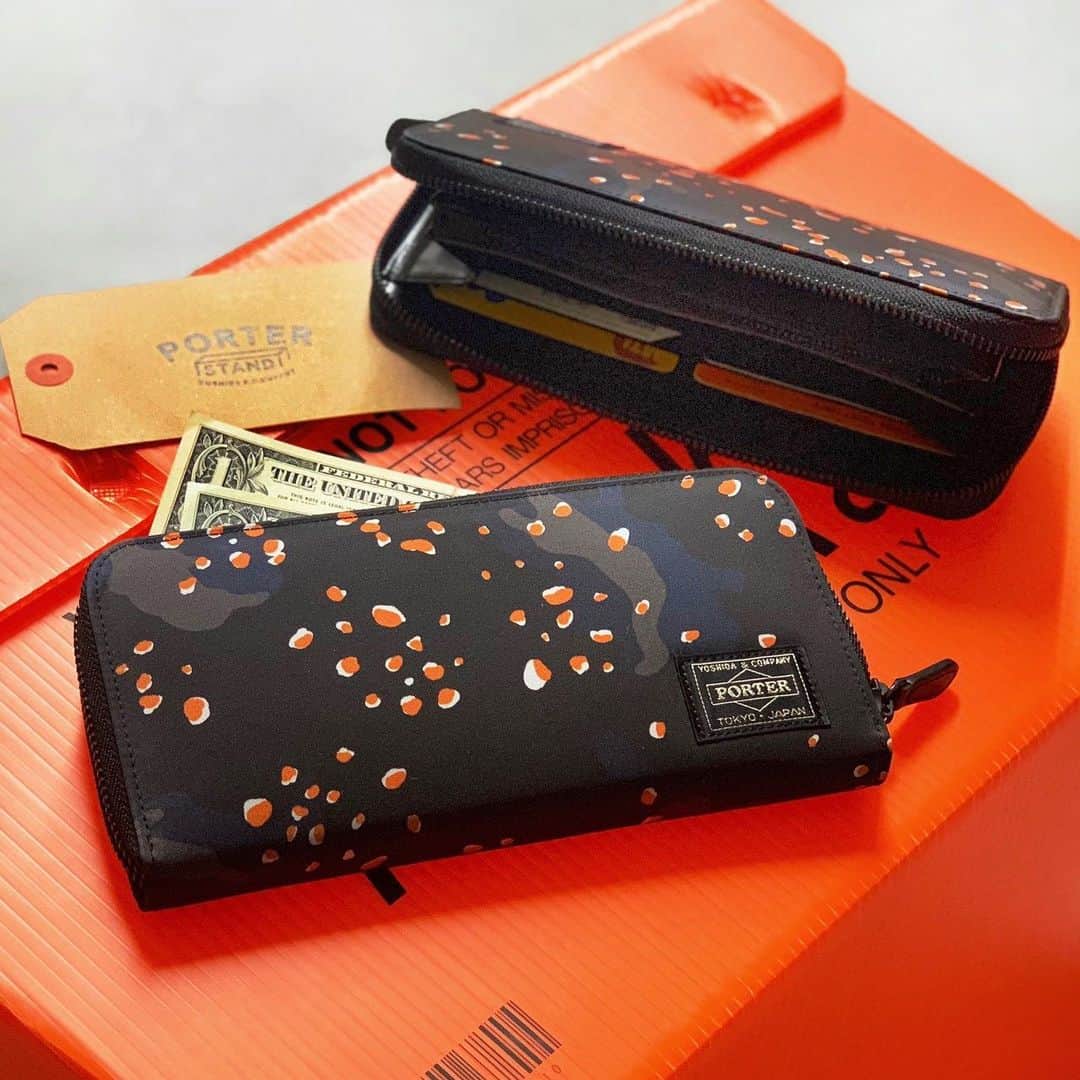 のインスタグラム：「「PORTER STAND」  おはようございます。 本日は発売以来、ご好評いただいている「PS CHIP CAMO」シリーズよりロングウォレットをご紹介いたします。砂漠地帯で多く用いられるチョコチップ迷彩を、PORTERらしい発色の良いオレンジカラーを差し色に、ブラックやネイビーのカモフラージュ柄でデザインしました。本日ご紹介するラウンドファスナーのロングウォレットは、収納力抜群。内装に多くのカードポケットや仕切りを設けており、カードやレシートなどを整理しやすい仕様となっています。ギフトにもおすすめのアイテムです。 是非店頭でお手にとってご覧ください。  PORTER STANDオリジナル PSチップカモ ロングウォレット ￥23,000（税別）  #yoshidakaban #porter #luggagelabel #吉田カバン #ポーター#porteryoshida #porterflagshipstore #madeinjapan #japan #porterstand #shinagawa #tokyo #station #kyoto #ps #chip #camouflage #longwallet #exclusive」
