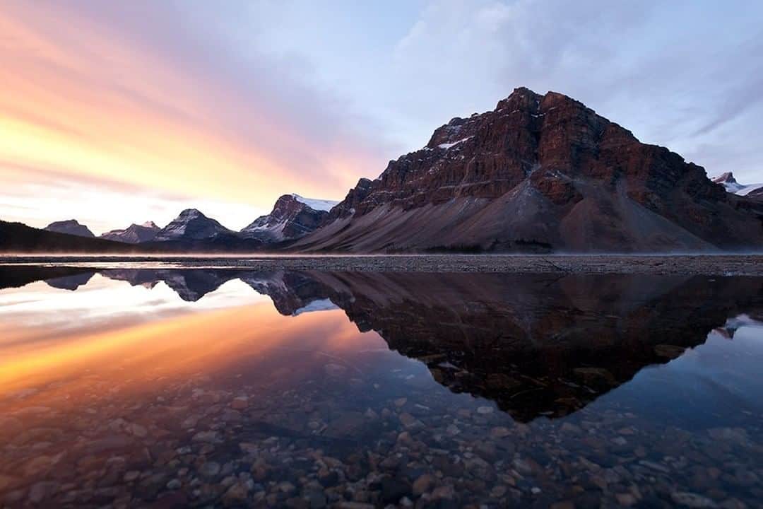 National Geographic Travelさんのインスタグラム写真 - (National Geographic TravelInstagram)「Photo by @daisygilardini | Bow Lake in Alberta’s Banff National Park is one of my favorite locations to visit during the fall. The tundra turns red, and at sunrise the lake is often steaming because of the temperature difference between the air and the water. I woke up early on this morning to catch the first light, but I soon realized that the stiff breeze would not allow for a good reflection. Instead of going back to the cabin to sleep, I decided to look around and enjoy the moment. While walking along the beach, I noticed a puddle. The depression in the ground where the puddle formed was deep enough to shield the water from the breeze. The magic happened when I got down flat on my belly and the perfect reflection appeared. Follow me @DaisyGilardini for more images and stories behind the scenes. #canada #bowlake #banffnationalpark #sunrise #reflections」1月21日 14時09分 - natgeotravel
