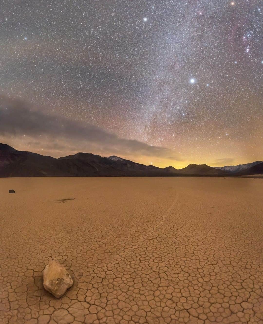 National Geographic Travelさんのインスタグラム写真 - (National Geographic TravelInstagram)「Photo by @babaktafreshi | At the remote Racetrack Playa in Death Valley National Park, California, I was standing next to one of the mysterious sailing stones, looking up to Sirius, the brightest star in Earth’s night sky, and the constellation Orion (top right). On the horizon is the glow of Los Angeles, still faintly visible from 190 miles (300 kilometers) away. These moving rocks, originating from the nearby mountains, are a geological phenomenon. They naturally move along this high-altitude, smooth valley floor on a very thin nighttime surface of ice sheets, driven by wind.  Explore everything from the Earth to the universe with me @babaktafreshi. #saveournightsky #twanight #deathvalley #nightphotography #nationalparks」1月22日 18時09分 - natgeotravel