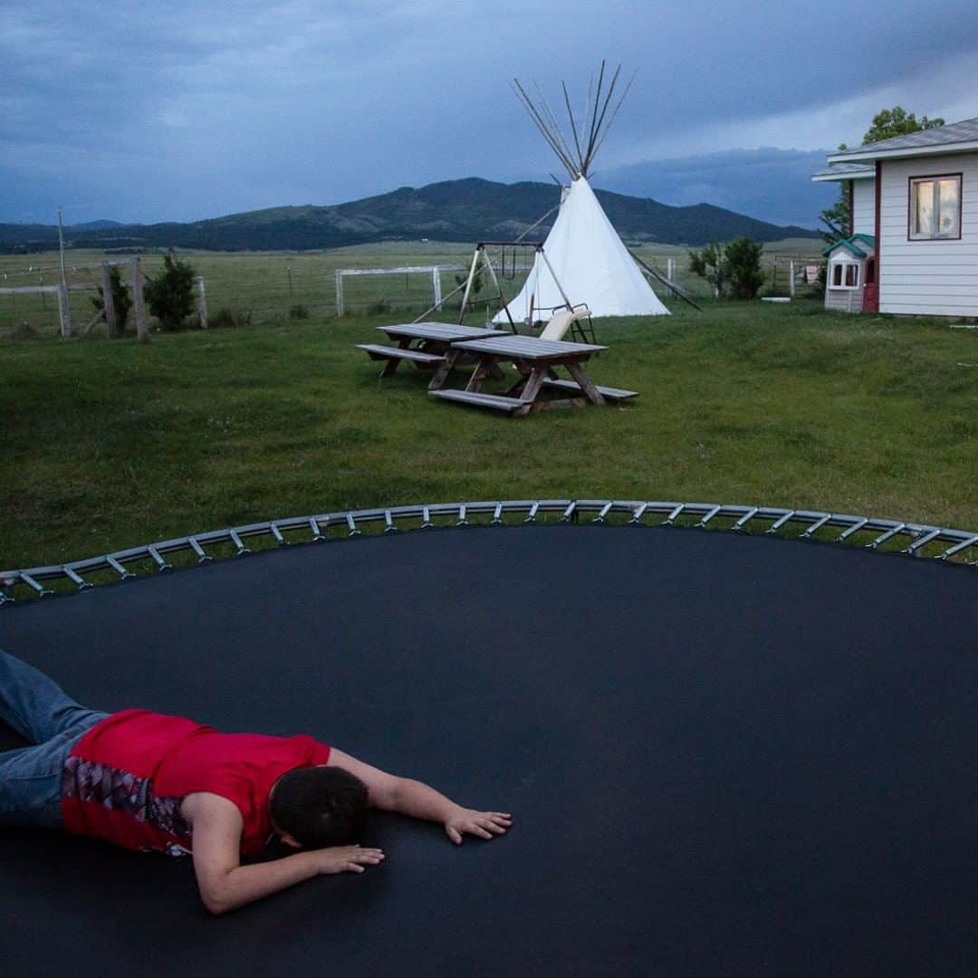 のインスタグラム：「Photo by @amytoensing | Long solstice evenings provide plenty of trampoline time in the Werk family’s backyard in Hays, Montana. The Werks, members of the Aaniiih tribe, live and ranch along the edge of an ambitious conservation project in central Montana. The American Prairie Reserve (APR), an independent, nonprofit organization, is working to create the largest nature reserve in the lower 48 by stitching together 3.5 million acres of private and public lands. APR’s goal is to remove all the cattle and replace them with 10,000 free-roaming bison, and allow this temperate grassland, one of the four left on our planet, to thrive and be forever protected. However, most ranching families that have worked this land for the last 125 years see this as a threat to their way of life. Many Native Americans, like the Werk family, whose ancestors lived on this land for tens of thousands of years before being forcibly pushed off, are wary of outsiders taking over but thankful to see the return of the bison. Says Toby Werk: “We know firsthand what it’s like to be taken off the land and destroyed.” In the February issue, the story “Prairie Divide” looks at this complex conservation project and how it’s impacting the land and the people who live there.」