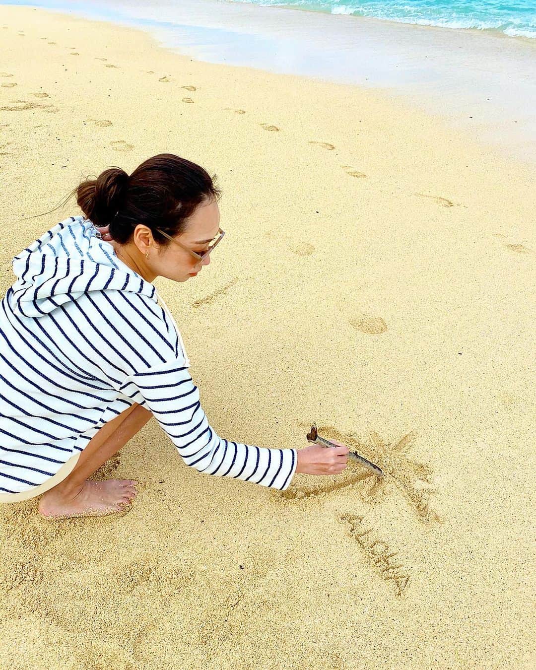 石田美奈子のインスタグラム：「ℍ𝕒𝕨𝕒𝕚𝕚. . おはようございます☺︎ #ラニカイビーチ で何度か試行錯誤した砂浜への落書き🌴 . 今日の東京は雨ですね。 昨日から寒すぎて、ハワイの暖かさが恋しいです🤣 . 1月のハワイはそんなに暑くなくて、薄手の長袖トップスにショートパンツとか、Tシャツにロングのボトムスに羽織りものを持ち歩く、くらいの服装がちょうど良かったです(⑅ˊᵕˋ⑅)✨ . このトップスもショートパンツもハワイで現地購入したお気に入り！♡ . ✈️ → #minako_trip . #hawaii #hawaiistagram #lanikaibeach #ハワイコーデ #ハワイ購入品」
