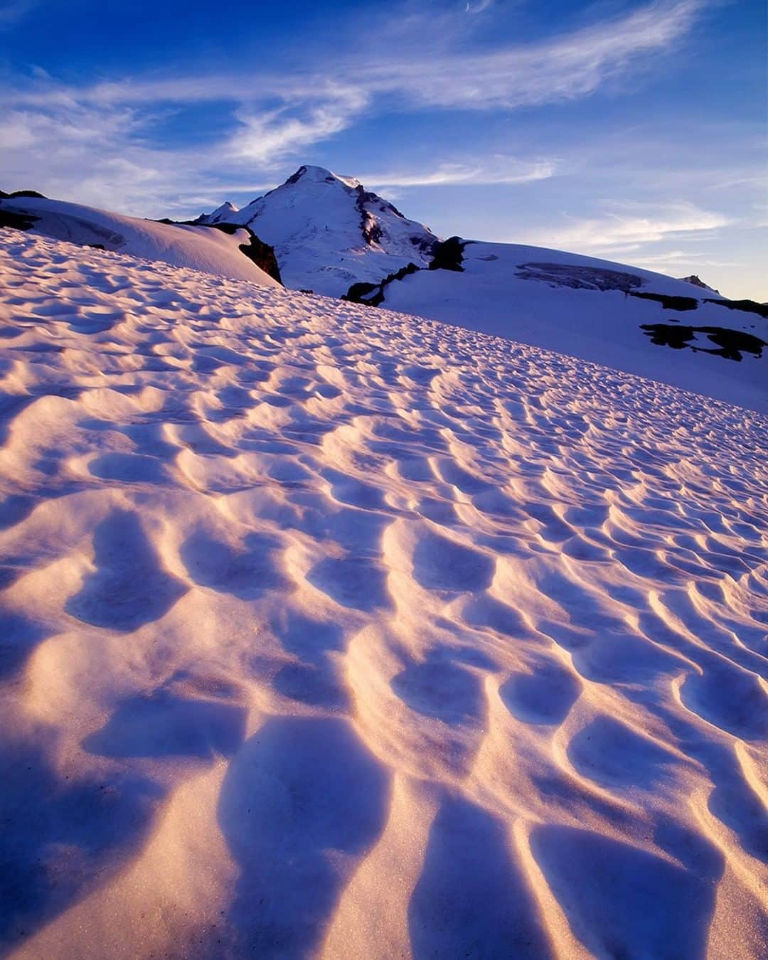 National Geographic Travelさんのインスタグラム写真 - (National Geographic TravelInstagram)「Photo by @stephen_matera | Meltwater depressions in the snow, called sun cups, catch the last light of the day below Mount Baker in the Mount Baker Wilderness. Washington State has five very prominent volcanoes that are heavily glaciated and significantly higher than their nearby peaks. These five are Mount Rainier, Mount Adams, Mount St. Helens, Glacier Peak, and Mount Baker. They're all beautiful and inspiring, and stand head and shoulders above the non-volcanic peaks of the Cascades. At 10,781 feet (3,286 meters), Mount Baker is the third highest volcano in Washington State.  Follow me @stephen_matera for more images like this from Washington and around the world. #volcano #washington #volcano #glacier」1月26日 14時09分 - natgeotravel