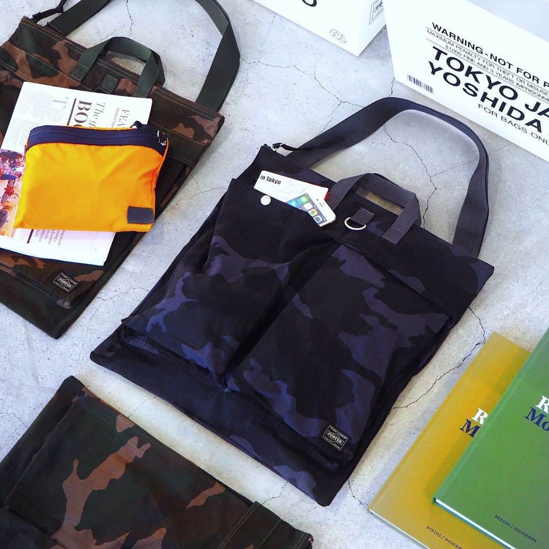 のインスタグラム：「こんばんは。 本日は、PORTER flagship storeにて展開中の「PLATOON（プラトーン）」の2WAYヘルメットバッグをご紹介いたします。オリジナルで製作したコットン×ナイロンのリップストップ生地に、カモフラージュ柄の中でも代表的なウッドランドパターンのプリントを施したパッカブルシリーズです。ナチュラルなコットン糸と耐摩耗性に優れたコーデュラ®ナイロン糸を、リップストップ（格子状）に織り上げることで、軽量で高強度でありながら風合いのある生地に仕上げました。フロント部分には1910年代のミリタリーコートのディテールをモチーフにしたDカンを取り付け、アレンジできる仕様にしています。本日ご紹介する2WAYヘルメットバッグは、手持ちと肩掛けの両方でお使いいただけます。内装には本体を畳んで収納できるレスキューオレンジカラーのポケットを設け、折り畳んでコンパクトにする事が可能です。普段使いはもちろんトラベルシーンにもおすすめのアイテムです。 是非、店頭でお手にとってご覧ください。  プラトーン 2WAYヘルメットバッグ ¥22,000（税別）  #yoshidakaban #porter #luggagelabel #吉田カバン #ポーター #porteryoshida #porterflagshipstore #porterstand #kurachikabyporter #potr #madeinjapan #japan #instagood #instalike #instabag #omotesando #marunouchi #osaka #platoon #2way #helmetbag #military #woodland #olivedrab #midnightnavy #packable #exclusive #trip #tlavel」