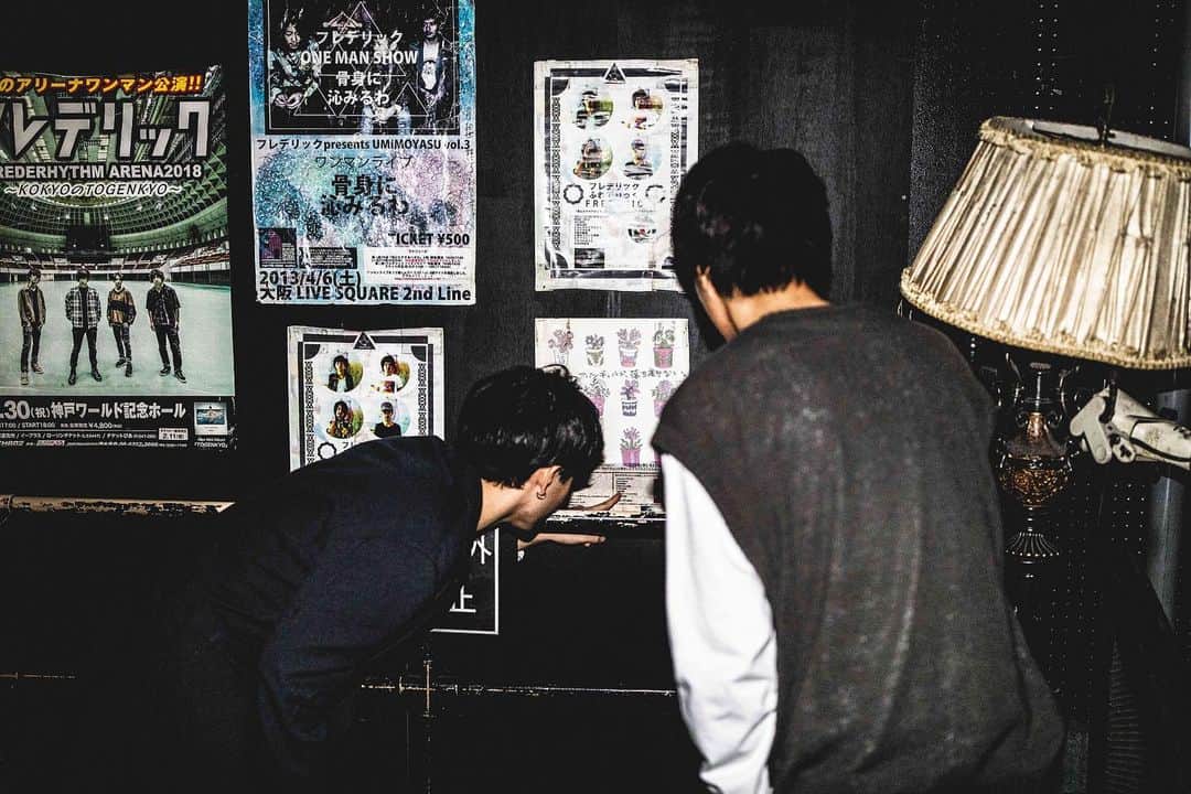 三原康司のインスタグラム：「2020.2.11 kobe VARIT 「フレデリズムツアー特別公演 2020-LIGHT LIVE♩=90～130-」 昔のフレデリックのポスターを懐かしむ隆児と康司  VARITさんが昔のを掘り出して張ってくれてた、ありがたい。  Photo by @nabespg  #フレデリック #フレデリズム #FRDC #神戸VARITのやさしさ #昔のアー写の方が歳とってる気がした #金髪髭の三原康司がいた #いつの時代も楽しんでるな」