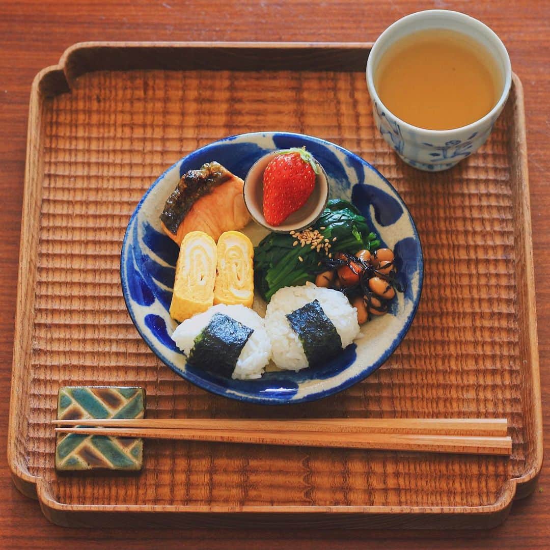 Kaori from Japanese Kitchenのインスタグラム：「在宅勤務中の朝昼ごはん。やちむんを使って沖縄への想いをめぐらす昼休み。 ・ こんばんは。 在宅勤務中の朝昼ごはん。 とにかく準備に時間をかけたくなかったので #パルシステム の冷凍鮭をチンして家にある総菜を盛り 小さく握ったおにぎりを添えて10分で終了。 準備〜食べる〜洗い物まで 1時間以内で収まりました✌🏻 元々インスタにアップするつもりはなく 在宅勤務の気分転換に盛り付けたら いつも以上に綺麗に盛り付けられて せっせと記念撮影(おい、在宅勤務笑) そういう事情で味噌汁は無し。 満腹だと眠くなるし 腹7分目くらいがちょうど良いかな、と 思ってましたが案の定夕方には腹ペコでした笑 楽だし自分自身も目で楽しめたし このスタイルはアリよりのアリ。 ・ iPhone7と比較したらわかるように 器の大きさは5寸くらいと かなり小さなワンプレートです。 やちむんの青は料理をおいしく見せてくれますね。 あー沖縄旅行いきたいな。 安心して旅行へ行けるのはまだ先かな。 海外も国内も旅行の予定が立てられず 妄想ばかりが膨らんで困ってます。 …以上、旅行好きのしょーもない独り言でした。 今日もお疲れ様でした。 ・ 【おしながき】 三角こにぎり 卵焼き ほうれん草のごまポン酢和え ひじきと大豆の煮物 焼き鮭半身 いちご ＊今日は薬膳走り書きはお休みします＊ ・ Hi from Tokyo! Here's late Japanese breakfast:Riceballs,grilled salmon, rolled egg omelette, boiled spinach, simmered hijiki seaweed and strawberry as a dessert. ・ ・ 2020.03.12 Thu ・ ・ #japanesemeal #washoku #breakfast #朝ごはん #おうちごはん #早餐 #아침밥 #薬膳 #うつわ #和食器 #自炊 #やちむん #落合芝地 #ワンプレート #卵焼き #在宅勤務」