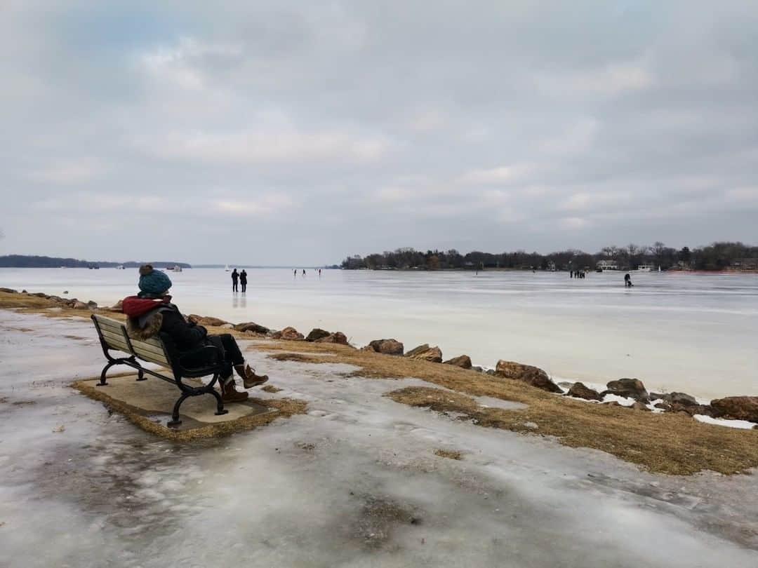 National Geographic Travelさんのインスタグラム写真 - (National Geographic TravelInstagram)「Photo by Robbie Shone @shonephoto | A tourist sits on a bench and watches ice-skaters on the frozen surface of Lake Minnetonka, Minnesota.」3月13日 17時08分 - natgeotravel