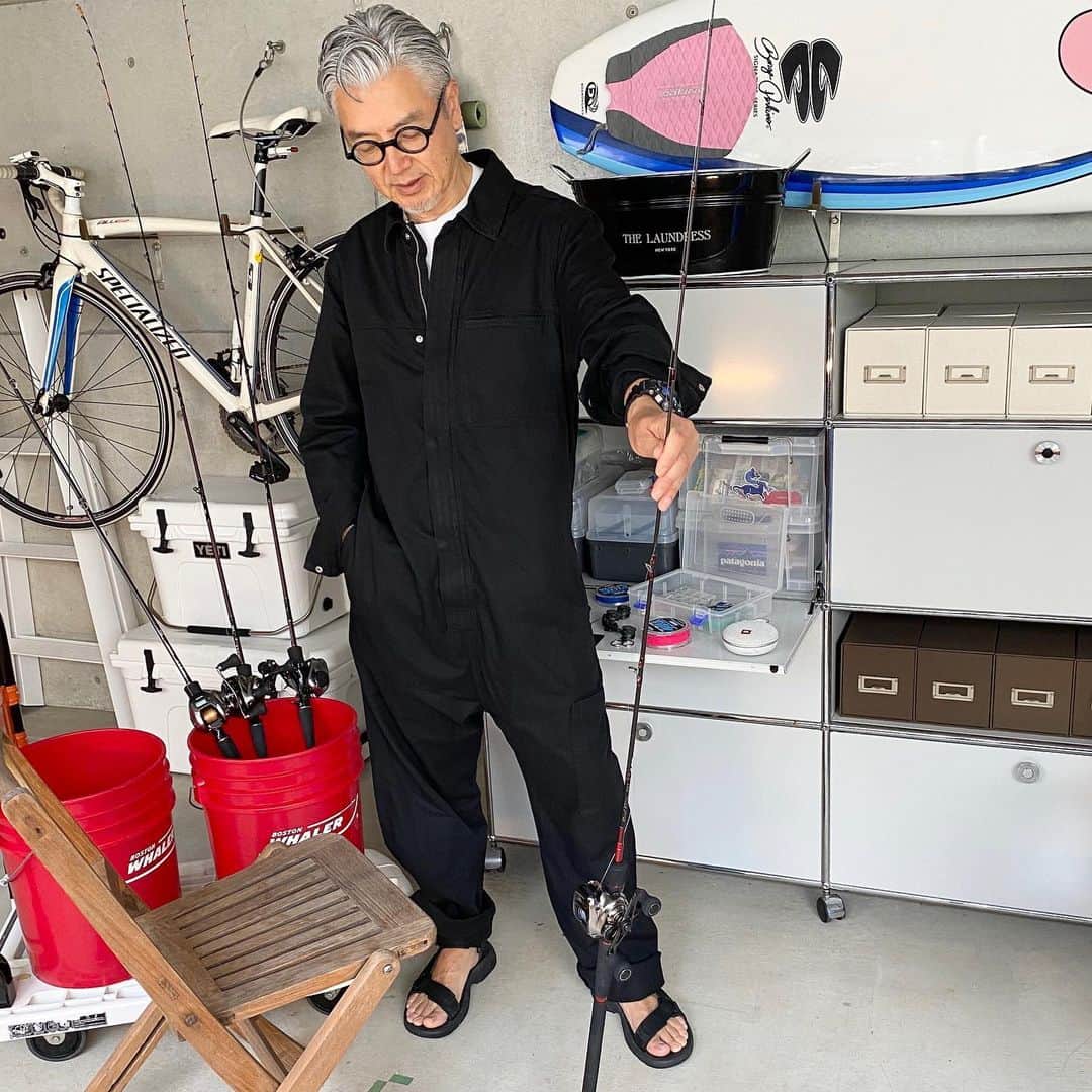 のインスタグラム：「【40歳男子の「きょう何着てた？」／#26／コスのオールインワン／藤村雅史さん（アートディレクター）】 たとえ誰にも会わなくても、おしゃれにだけは手を抜かない。そんな服好きたちの日々の着こなしを、リモートスナップ！ーー  オールインワン：コス サンダル：テバ  外出自粛で大好きな釣りにも行けない日々が続いていますが、道具はほっとくと痛んでしまうのでこまめにケアしています。自宅作業用にオーバーオールに続いてツナギがあったらラクだなと思っていたところ、UOMO6・7月合併号『買ったもん勝ち！』特集でスタイリスト小沢宏さんがコスのツナギを紹介しているのを見て、早速オンラインストアで探してみるも残念ながら完売でした。ボタンがかわいかったのに…と残念な気持ちでそのままぐるぐるサイト内をリサーチしていたらオーガニックコットンのボイラースーツを見つけました。こちらはジップアップタイプでよりガチワークな雰囲気でしたが、黒だし着やすいかなと思ってポチ。届いて早速着て作業してみると、とても動きやすくて着心地がよかったので、結果的にいい買い物でした。足元はテバのサンダルで抜け感を出しています。まあ、自粛期間が終了してもこれを着てUOMO編集部に行ったらみんなに突っ込まれまくりそうなので、、しばらくは自宅着として愛用する予定です。  #cos  #teva  #コス  #テバ  #オールインワン #ボイラースーツ　#mensfashion ＃stayhome  #おうち時間  #在宅勤務  #リモートワーク #在宅UOMO  #藤村雅史」