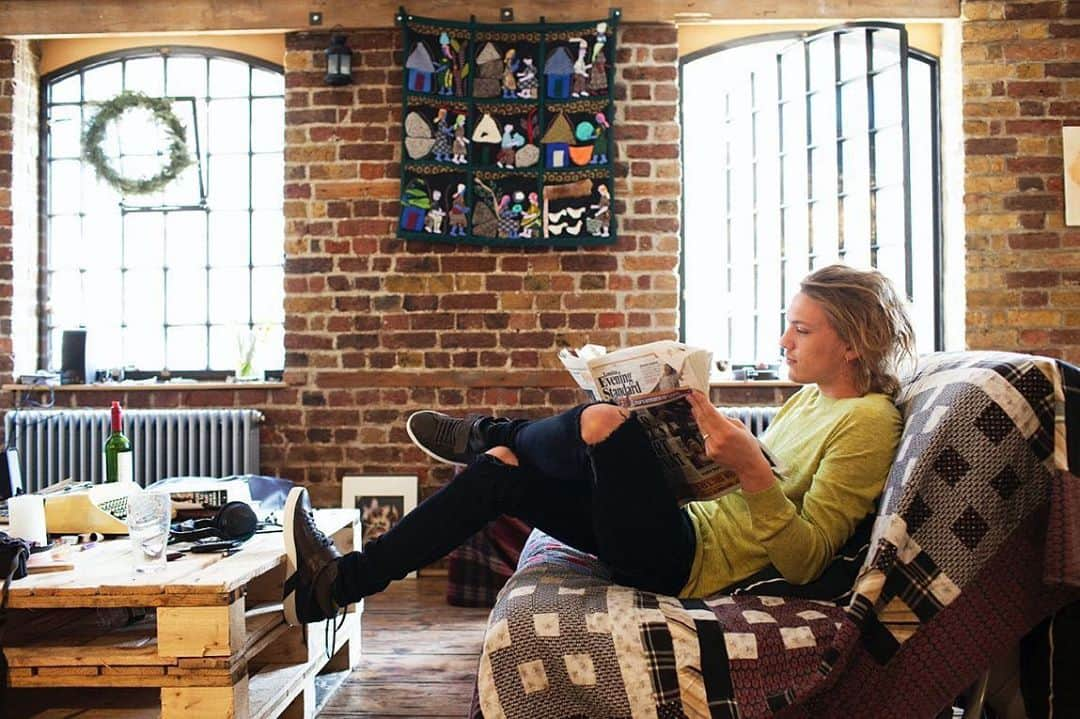 ジェイミー・キャンベル・バウアーのインスタグラム：「I’ve always loved this picture so here it is on the internet. It was taken by @theselby in my first apartment in London. Some fun facts about this picture. 1. The hanging on the brick wall was a gift from Gandalf, I mean Sir Ian McKellen 🥰. I still have it 2. The typewriter is one of my most favourite things in the world and was also a gift. 3. Although there is a Wreath hanging in the window this photo was not taken at Christmas. I had refused to let the festive Yuletide end. 4. The table... urmmm yeah those were pallets that someone had thrown on to the street so I borrowed them. Waste not want not.  Okay. Bye now. Just a bit of fun for a Wednesday. Hope everyone is safe. All my love. Jamie. X」