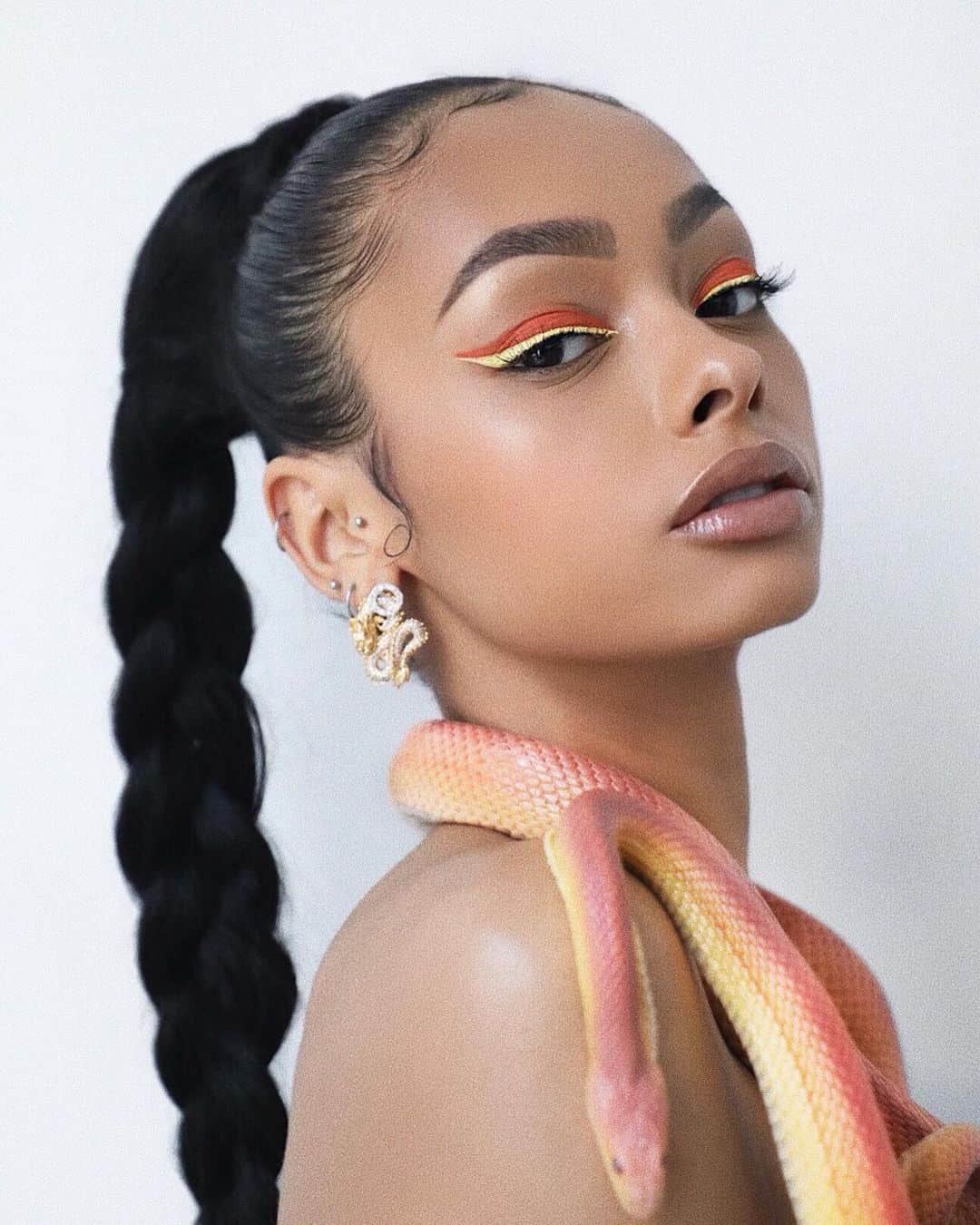 ジェイデ・ピアスのインスタグラム：「The snake wore it better. | 🐍  Eyeliner - the yellow is @fentybeauty vivid liquid eyeliner in shade “banana blaze”. The orange is @colourpopcosmetics ultra matte liquid lipstick in shade “what’s the stitch” with shade “Sonia” from the @certifeye affinity palette on top. Hair - @beauty_worksonline 20” beach wave invisi pony tail in shade “jet black”. Earrings - aren’t actually earrings lol. Used the pendent from one of my @remesorajewellery necklaces and somehow made it into an earring lmao.」