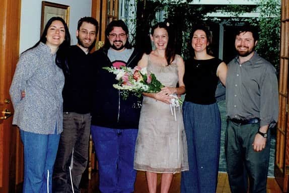 ケヴィン・スミスのインスタグラム：「HAPPY 21st ANNIVERSARY to that girl I married way back in the 90’s, @jenschwalbach! She wed me barefoot and 8 months pregnant, as if we were characters in a movie about a shotgun wedding. We barely knew each other so you could forgive folks back then for thinking “This will never last...” And while there were times both of us were inclined to agree with our Doubting Thomases, today we’re 2 decades-plus into a hasty bet we wagered in our late 20’s. People aren’t likely designed to be together for as long as we humans opt to cohabitate. We’re animals too - and the majority of animals don’t mate for life. But it’s still an ideal our species strives for: a dream of a romance so epic, it can last our whole lives and survive the test of time. As we mark the start of our Blackjack Year, I barely recognize the couple in this photo - the children who made a choice with no knowledge of who they’d eventually grow up to be. We’re both now much smarter and informed than these kids were when they took the plunge. In truth, this was the most challenging year of our marriage. But in every relationship, sooner or later, there’s some shit to deal with - so sometimes, you just have to wipe as well as you can, hike your Jorts back up, and move on with the day. Look at the folks in this photo: everyone’s happy and hopeful because the movie’s just starting, and falling in love is the easy part. But if you can maintain a marriage when it’s less romantic and more realistic, one day you might get lucky enough to see how the movie ends! I love you, Jenny Schwalbach! Thanks for taking me to the movies for the past 21 years! I’m in no rush, but I can’t wait to see how the movie ends! Hopefully we blow up the Death Star and both get medals! #KevinSmith #jenschwalbach #jenniferschwalbach #married #anniversary #90s」