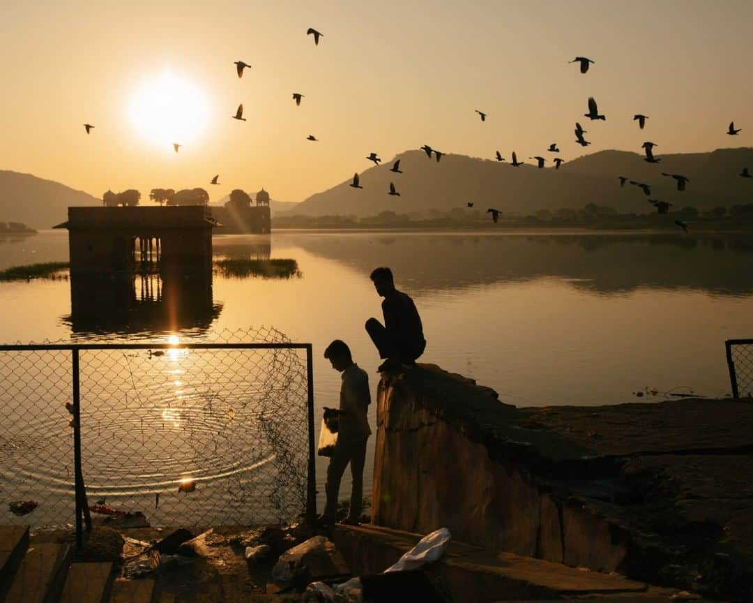 National Geographic Travelさんのインスタグラム写真 - (National Geographic TravelInstagram)「Photo by @MichaelGeorge | During a trip to India last year, I woke up on my last day for a sunrise walk along the Man Sagar Lake with a friend. We were in a flurry of morning activity, as people set up small shops, took portraits of one another, and fed the various animals that live around this beautiful area. In the distance, we could see the Jal Mahal (Water Palace). It's funny how you can go months without finding a great picture, and then sometimes you get 20 great pictures in a single morning. This was one of those lucky days. These two men were feeding the birds (and soon, the monkeys) as we walked by. #mansagarlake #india #jalmahal #waterpalace #sunrisewalk」4月29日 1時06分 - natgeotravel