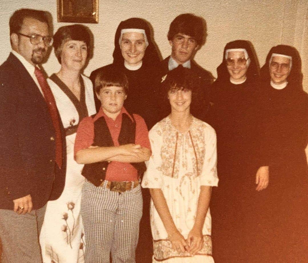 ケヴィン・スミスのインスタグラム：「MARCH OF THE PENGUINS! My brother Don, my sister @virginia_in_vienna and I all attended @olphstagnes (Our Lady of Perpetual Help) in my hometown of #highlandsnj. Pictured left to right: Dad, @donsgirlgrace, me, my 8th grade teacher Sister Theresa, Virginia, Don, principal Sister Gloria, and my third grade teacher Sister Anne (who left the convent years later). I’m all of 8 years old and that vest is wearing ME as I cross my arms, thinking it will hide my burgeoning belly instead of showcasing it. The Franciscan Sisters of the Infant Jesus arrived at OLPH in 1983, replacing older Nuns from a different order who still favored physical discipline to keep kids alive (and obedient). But even though these new Sisters wore more layers of a habit (even in the summer), they were much more progressive: God wasn’t to be feared, He was to be loved, they taught us. Sister Anne was the first teacher to notice that I was into acting, so she cast me in a Parable play as a greedy glutton who goes to Hell (a role I’d keep playing up until my heart attack). Sister Theresa, though? She nurtured my interests in theater and writing AND public speaking. Sr. T cast me as Cromwell in “A Man for All Seasons” and then had me deliver our 8th grade graduation address, even though I didn’t have the marks of a Valedictorian. But Sister Theresa defended her choice by asking the class point blank “With the exception of our Lord Jesus Christ, who loves to talk to a crowd more than Kevin Smith?” We are the sum total of all the people we ever meet, and Sr. Theresa’s belief in me as a performer likely changed the course of my life. If this adult in charge of me for six hours a day believed I was good at something, then I thought maybe I should lean into that thing. My brother Don still speaks with Sister Theresa periodically, so I know she was less-than-thrilled with the movies I’ve made (especially Dogma). I suspect she carries Catholic guilt about playing a role in unleashing me on the world, but I wish she could see all the people whose lives she’s effected simply by teaching me and telling that kid he might be good at a thing. Thanks to Sr. T, I turned that thing into *my* Habit! #KevinSmith」