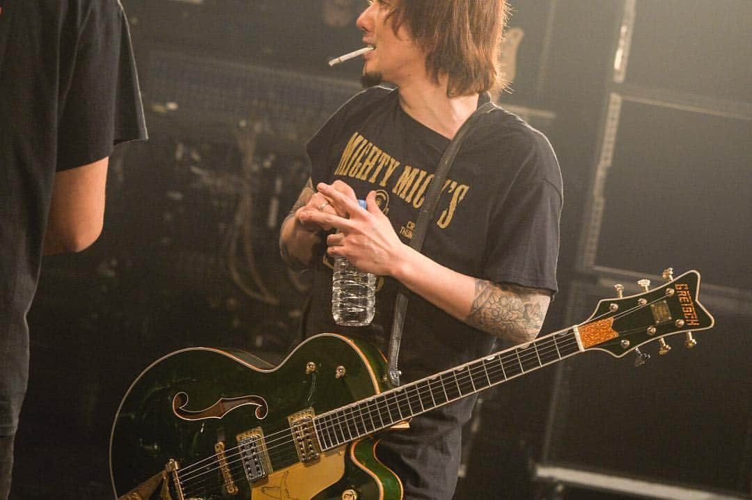 横山健さんのインスタグラム写真 - (横山健Instagram)「2018.3.2@ Blitz, Akasaka, Tokyo “Punkrockers Bowl Vol.37...?” ライブ中の憩いのひと時。ステージ上でタバコを一服。この時間好きなんですよ。  最近ステージ上でタバコ吸うミュージシャンあまりみなくなったね。みんなタバコ止めてんのかなぁ？まぁどうでもいいんだけどね。  そもそも一服する時間なんかないほどの緊張感の中でやるのがバンドというものの美学というなんとなくの常識もありましょう。  だから珍しい写真だといえますよね。  でもオレは、そりゃ一服してる時は緊張感ないけど、終わったら……いや、ほぼいつもないね。  それには理由があるんです。緊張は本来の力を出させなくさせるから、悪なんです。オレにとってはね。他人様のことは知らんよ？オレにとっては必要以上の緊張感は悪なんずら。  誰もそんなこと教えてくれなかったけど、道（ストリート）が教えてくれたんずら。  Photo by teppei kishida  #gretsch #gretschguitars #kennyfalcon #punkrockersbowl #pizzaofdeath #kenband #kenyokoyama #横山健 #道かっこストリート」3月7日 11時01分 - kenyokoyamaofficial