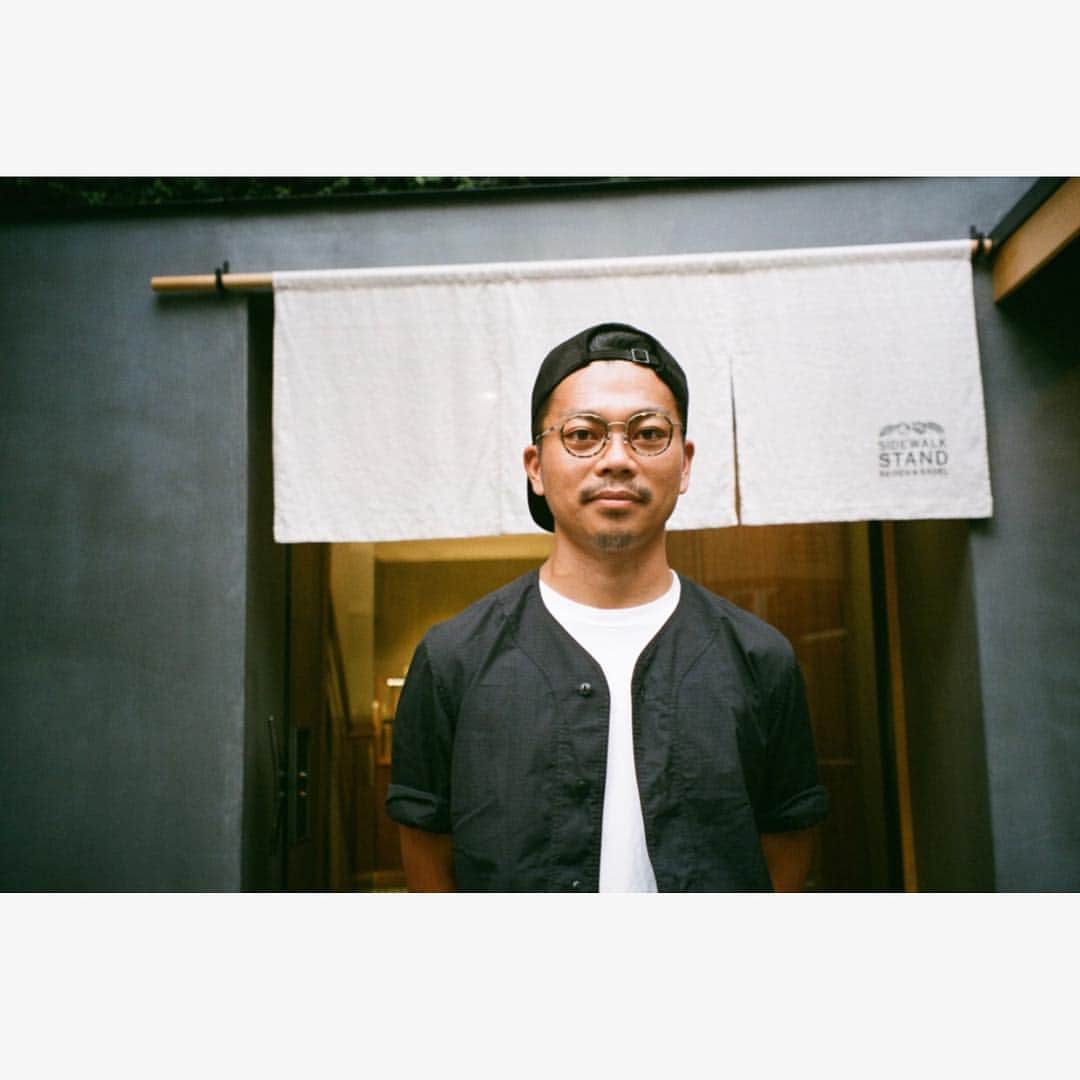 Zoff Officialのインスタグラム：「TOKYO GUIDE MAP EYE am a HERO! . 小林修人さん/焙煎士 【中目黒_SIDEWALK STAND BAISEN&BAGEL 】 . ZO181002_49A1 ¥9,720(税込) . PHOTOGRAPHY 草野庸子 . こだわり自家焙煎コーヒーともちもちベーグルの最強タッグ . 最先端がゆるりと共存する中目黒。 特に川沿いは人の流れも穏やかで、街ブラにちょうどいい。 こちらはnonnativeやvendorでおなじみ、TNPが手がける「SIDEWALK STAND」の新店。蔦の絡まる古民家の暖簾をくぐると、とびきり美味いコーヒーと自家製ベーグルが出迎えてくれる。「目指すのは飲んだあと余韻が残るコーヒー。 コクや甘さが引きたつよう中深煎りに仕上げています」と語るのはバリスタ歴6年の小林さん。 豆は店内の立派な焙煎機でロースト、天然酵母を使ったベーグルは噛み応え満点なのにNY式にありがちな固さは一切なく、次の日でも美味しく食べられると評判だ。 スタッフの雰囲気もナイスで、チルアウトのつもりがついつい長居したくなる。 . SIDEWALK STAND BAISEN&BAGEL / Nakameguro is where cutting edges unhurriedly coexist. Flow of people are especially calm by the river side, and is perfect for town strolling. This is a SIDEWALK STAND’s new restaurant operated by TNP which is familiar with “nonnative” and “vendor.” After passing through the Japanese traditional shop curtain hanged on an old Japanese house twined with ivies, you’ll be welcomed by delicious coffees and homemade bagels. Mr. Kobayashi, a barista with six years of experience, says “My goal is to produce a coffee which lingers after drinking. I serve medium roasted beans for its sweetness and richness.” Beans are roasted by the fine roasting machine in café, and the chewy bagels made from natural yeast does not have the typical hardness of the NY style bagels, and are popular for being delicious even on the following day. The nice atmosphere of staffs makes you want to stay longer. . #zoff#fashion#glasses#eye#eyewear#eyewearstyle#new#lens#optical#メガネ#tokyo#tokyoguidemap#eyeamahero」