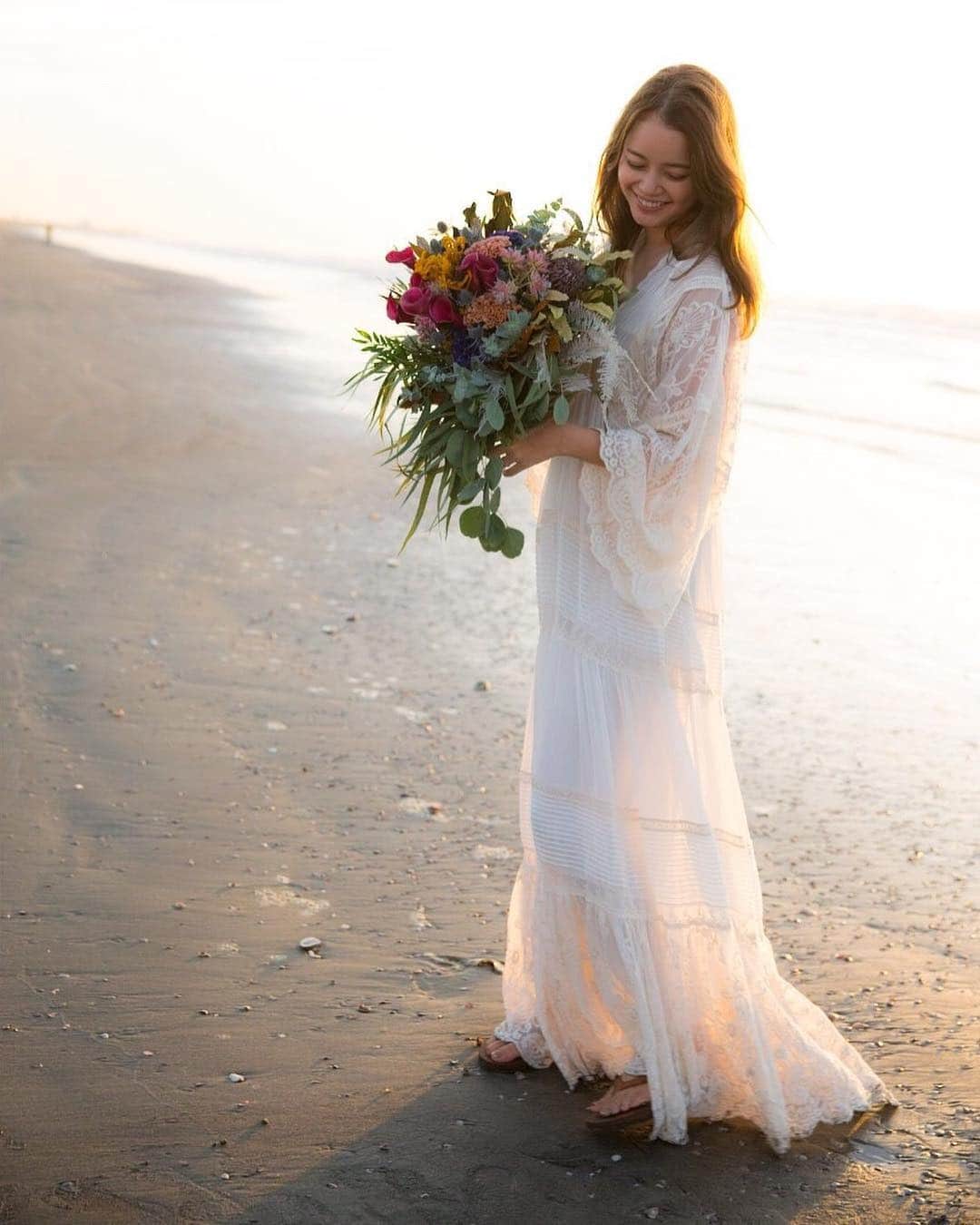 のインスタグラム：「🌼前撮りドレスのおはなし🌼  結婚式、披露宴が決定したのは 確か5月で 「よし！どんなドレス着よう😍」 とワクワクしていた私。  その前に前撮りで着るドレスを考えなきゃ と思い…ネットサーフィンの毎日が始まり🏄‍♀️ 私も旦那も海が大好き！ 前撮りは絶対絶対絶対！海で撮りたいという 思いがあったので、海に合って 自然体で撮れるドレスを探していました💛  そこで出会ったのが @spell  @spell_bride  のドレス。オーストラリアのブランドで 前々から雰囲気が好きだったお洋服で ドレスもあると知り、すぐにポチり😝  丁度、お腹もぽっこりしてきてたので、締め付けられずふんわり サラッと着れるドレスに出会えて良かった😭✨ 旦那もナチュラルな雰囲気に合わせて 麻のシャツにベージュのパンツ。  そして二人とも夏にずっと履いていた #rainbowsandals  のサンダル☺️キメすぎなくて 私達らしくて気に入っています🌈  #前撮りドレスのおはなし #wedding #beachwedding」