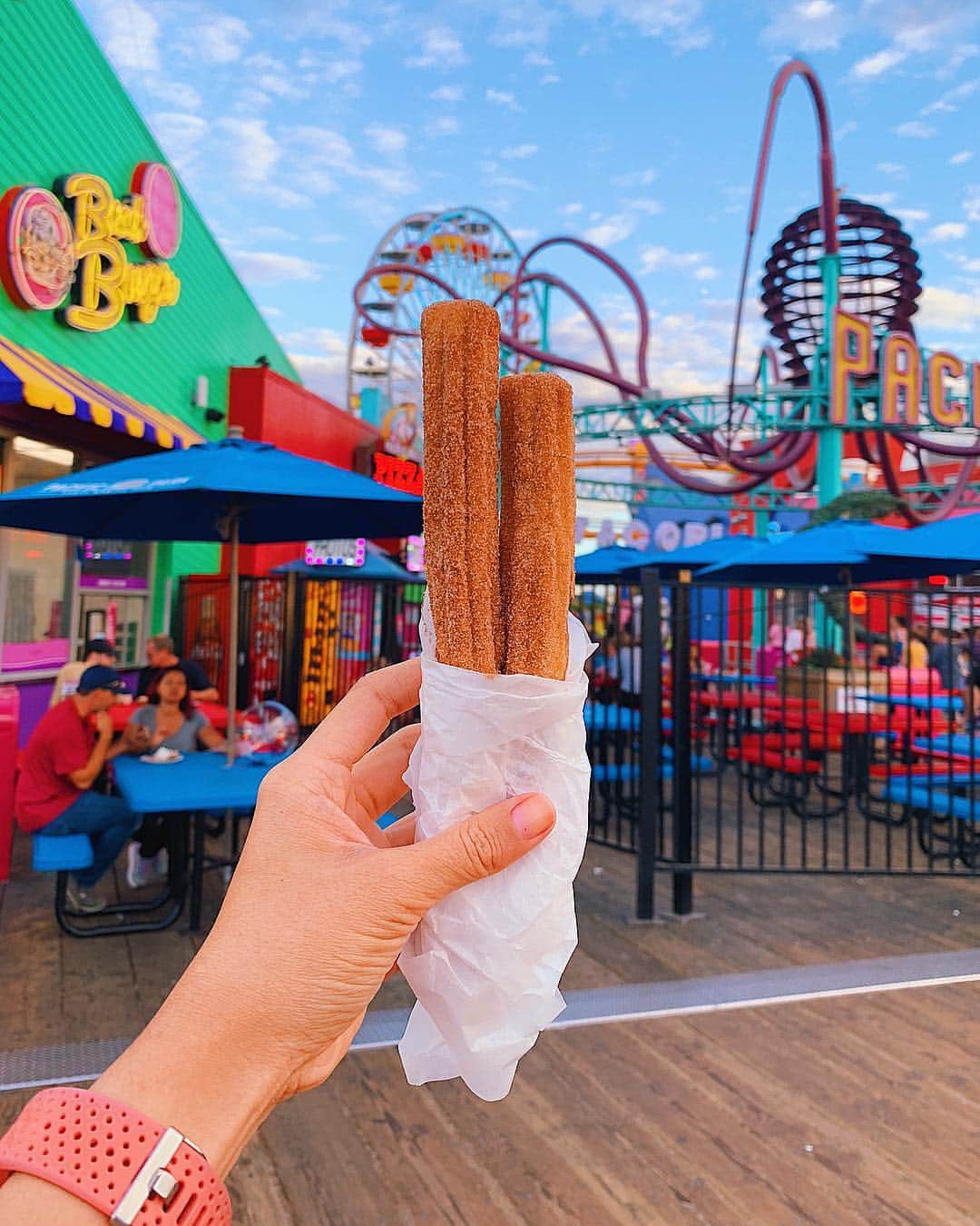 Girleatworldのインスタグラム：「🌴🎡🎢 Churros at Santa Monica Pier.  Honestly I wasn't even ready for an instagram photo as evidenced by my bare nails... but this is yet another special place in my heart. As poor students in LA, @op.118 and I didn't have a car. Yeah... the struggle was real. But that didn't stop us from exploring. We would brave the public transport, take Bus 8 or 12 to 3rd street promenade and walk down to the pier.  Santa Monica Pier was declared as the official end point of the legendary highway Route 66 on the highway's 83rd birthday. Nowadays you can see a road sign that marks the end of the trail at the Pacific Ocean.  On my visit to LA two months ago, @op.118  and I revisited the place and sat on a bench until sunset. It was truly the most beautiful sunset I've seen in a long while.  Sadly today California is fighting horrible wildfires and the sky probably doesn't look this clear for now. My thoughts are with those affected by Camp and Woolsey fire 😔  #shotoniphone #iphonexsmax #losangeles #santamonica #santamonicapier #california」