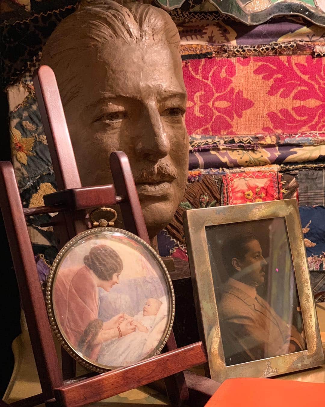 グロリア・ヴァンダービルトのインスタグラム：「A small corner on one of my tables.  The sculpture is of my father, whom i never knew, along with his photograph and a drawing of my mother and me, taken from a photograph. The backdrop is an old screen covered in fabric. I love the layering of objects which have history and meaning, but of course, soon I will re-arrange it, as one’s eye changes and sees it all differently.」