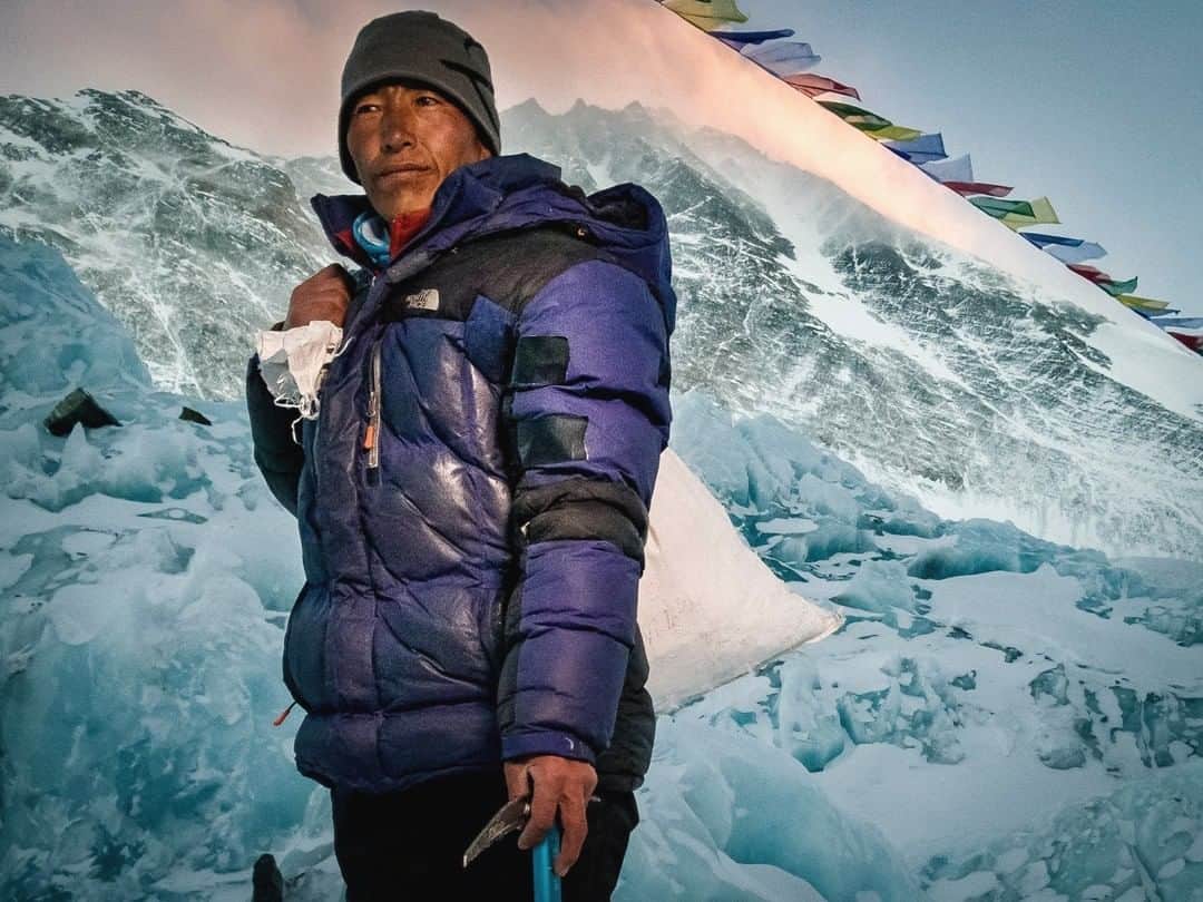 ナショナルジオグラフィックさんのインスタグラム写真 - (ナショナルジオグラフィックInstagram)「Photo by @coryrichards | Norbu, a Tibetan kitchen worker, stands for a portrait at 21,000 feet, below a fierce wind plume blowing off the summit of Everest. Every year, over a thousand people come to climb Everest. And every year, the climb is made possible by countless seemingly nameless individuals like Norbu. The infrastructure of Himalayan climbing is built, quite  literally, on the backs of people like him. Norbu shoulders a bag of freshly chopped glacial ice, which will be melted for water.  This is a trip he makes roughly 10 times a day for around six weeks. I will be attempting a new route on Everest this spring, and it’s people like Norbu make climbs like mine possible.  #followme @coryrichards for more visual storytelling #onassignment for #natgeo and previously unseen footage of the #culture #travel #adventure of the #Himalayas including my upcoming climb on the North East face of #everest.」3月21日 10時02分 - natgeo