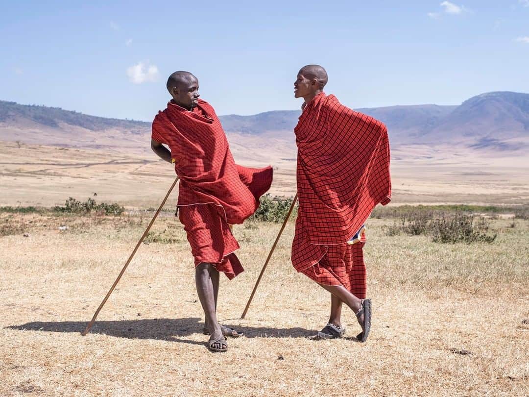 National Geographic Travelさんのインスタグラム写真 - (National Geographic TravelInstagram)「Photo by @gabrielegalimbertiphoto | Tanzania. Two Maasai men are talking outside of their village which is located just outside of the Ngorongoro crater. The Ngorongoro Conservation Area  is a protected area and a World Heritage Site located 180 km (110 mi) west of Arusha in the Crater Highlands area of Tanzania. The area is named after Ngorongoro Crater, a large volcanic caldera within the area. The conservation area is administered by the Ngorongoro Conservation Area Authority, an arm of the Tanzanian government, and its boundaries follow the boundary of the Ngorongoro Division of the Arusha Region.The 2009 Ngorogoro Wildlife Conservation Act placed new restrictions on human settlement and subsidence farming in the Crater, displacing Maasai pastoralists, most of whom had been relocated to Ngorongoro from their ancestral lands to the north when the British colonial government established Serengeti National Park in 1959. The construction of luxury tourist hotels in the Conservation Area allows people to access "the unparalleled beauty of one of the world's most unchanged wildlife sanctuaries", according to a government brochure, even as thousands of Maasai have suffered forcible eviction and have been denied access to water sources for their livestock. The Crater was voted by Seven Natural Wonders  as one of the Seven Natural Wonders of Africa in Arusha, Tanzania in February 2013. #tanzania #ngorongoro #crater #africa #maasai」3月21日 13時00分 - natgeotravel