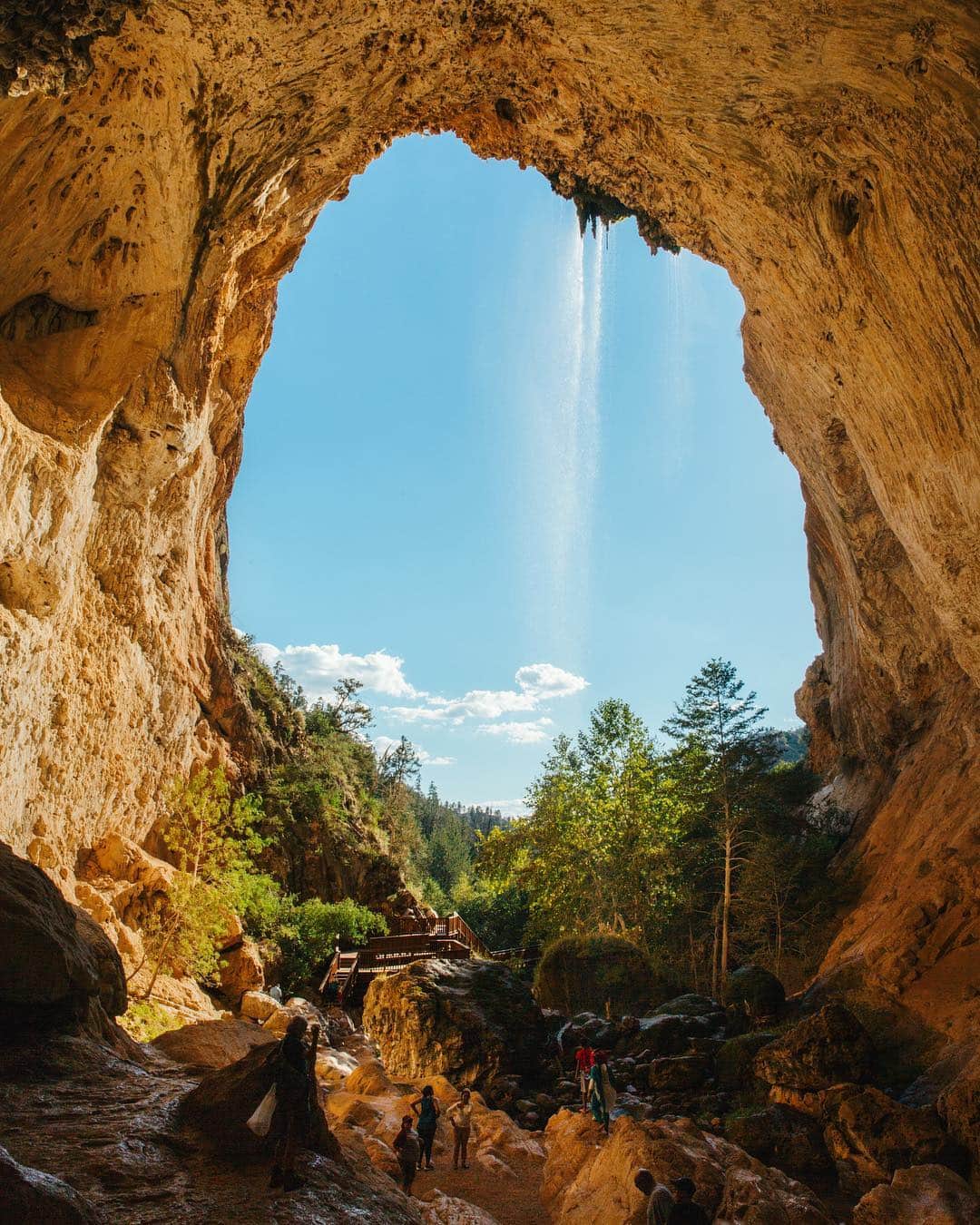 thephotosocietyさんのインスタグラム写真 - (thephotosocietyInstagram)「Photo by @MichaelGeorge // Near Payson, Arizona you can find the Tonto Natural Bridge, thought to be the largest natural travertine bridge in the world. For an idea of its size, look for the people at the bottom of this frame. This image was shot on assignment for @natgeotravel in September 2018. Our assignments can sometimes be a bit hectic schedule-wise, and this shot almost didn't happen. My assistant and I arrived at the Park and were guided in by a ranger. Up until our arrival, we weren't sure when or for how long the light was shining on the waterfall at the entrance of the bridge. Once we finally saw the falls (from above) I realized the sun was creeping towards the Canyon wall and in 5 - 10 minutes the backlit water would be cast in shadows. My assistant and I literally ran down the sidewinding steps (which I DO NOT advise) balancing our cameras and tripods, slipped around the extremely slick rock to get into position, and were able to get a few images approximately two minutes before the sun disappeared from the falls and they faded into the background. It is one of many times in my life I've found myself literally "chasing the light." // #paysonarizona #arizona #tontonaturalbridge #tontonaturalbridgestatepark #cavefalls #cave」3月26日 9時40分 - thephotosociety