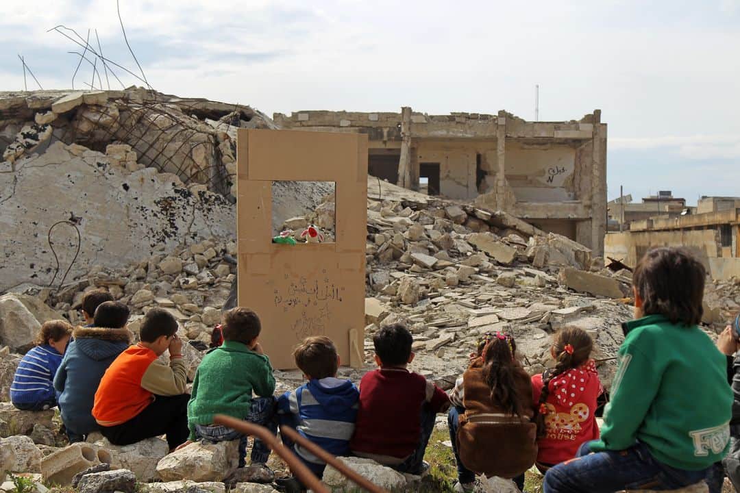 AFP通信さんのインスタグラム写真 - (AFP通信Instagram)「AFP Photo 📷 @amer.alhamwe - Children watch a puppet show performed by a Syrian actor, through a makeshift puppet theatre set up among the rubble of collapsed buildings in the town of Saraqib in the rebel-held northern Idlib province, on March 27, 2019.」3月28日 2時04分 - afpphoto