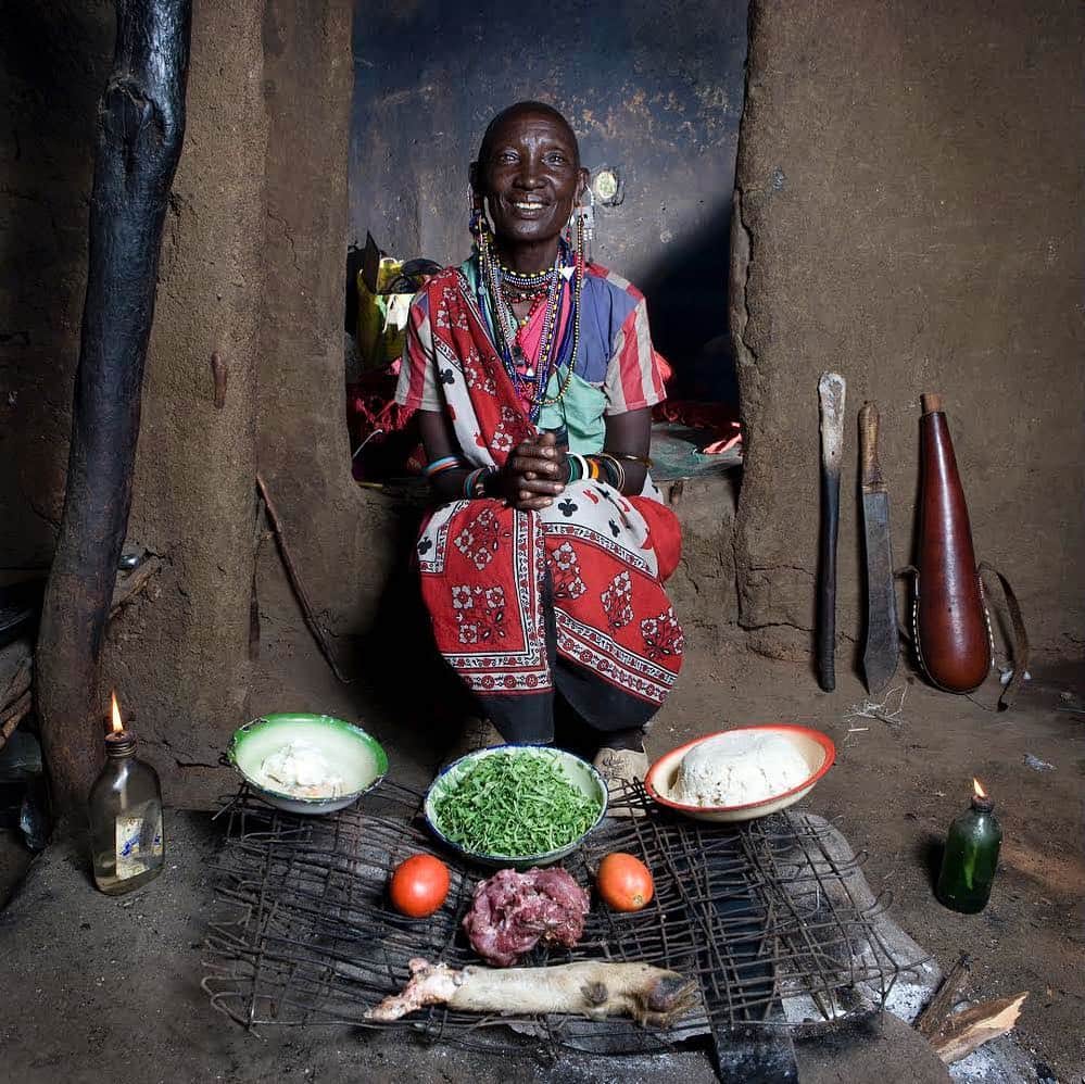 thephotosocietyさんのインスタグラム写真 - (thephotosocietyInstagram)「Photo by @gabrielegalimbertiphoto from his project IN HER KITCHEN / Grandmas always know how to cook! - Normita, 65 – Oltepessi Kenya / Normita lives in a hut made of mud and straws in a masaai village in Kenya. Her kitchen is nothing else than a small cooking area on the ground made of four stones and a metal grill placed on top. Every morning she lights a fire and keeps it on all day long. In her village there are 250 people and more than 500 animals among cows, goats and dogs. She is the chief of the village’s ninth wife and also the oldest woman. Cooking, collecting water from the river and gathering wood for the fire have always been her jobs. She has got 19 grown-up children and more than 40 grandchildren. They all live in the same village / MBOGA AND UGALI: Ingredients: Goat meat and a leg of goat, 50 gr cow’s fat, two tomatoes, 500 gr white corn flour, a plate of sukuma (a vegetable similar to spinach). Ugali is one of the most popular kind of food in Africa. In particular, in this area of Kenya, it is part of the everyday meal and it is at the base of almost any recipe. It is always eaten together with something else: meat, vegetables, fish and so on…  The first thing to prepare for our recipe is the orgali: Bring to boil a bit less than a litre of water with some salt. When it boils, add 500 gr of white corn flour, pouring them in the pot a bit at a time and stirring continuously until you obtain a dense mixture. Cook for about 10 minutes, turn the gas off and then let it cool.  Now you need to prepare meat and vegetables: - Chunk the goat meat into small pieces. Take the skin off the leg of the goat and strip the flesh from it. Put the meat in some water with salt. - Melt the cow’s fat in a saucepan and when it starts to fry, add two tomatoes chopped in cubes. - As soon as the tomatoes go mushy and create a sauce, add the chunks of meat and all the sukuma (cut in stripes). - Let everything cook for about 40 minutes. Taste it to see if you need more salt and add some if necessary.  When meat and vegetables are cooked, place them on the same dish with the orgali, as you can see in the photo.  #food #kenya #africa」4月1日 21時31分 - thephotosociety