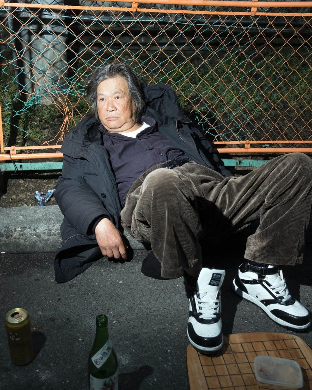 Q. Sakamakiさんのインスタグラム写真 - (Q. SakamakiInstagram)「Kamagasaki Portrait Series: Man chilling out in the early night at the site where his community friend was found dead by the roadside. Such a death is called “ikidaore” in Japanese. In Kamagasaki, it is said that few hundred people die in the ikidaore situation every year. Kamagasaki, Osaka, March, 2019. Kamagasaki is often called as the worst slum and/ or the most dangerous place in Japan. Yet many of them are so friendly and naive. So this time for many images, I have taken so at least somehow. However, it is true that many of Kamagasaki residents love the drinking so much and often tend to take the street fighting. Also there is an open secret — many residents, so many of them retirees, who live in poverty, are often exploited in their welfare system, even jobs, by middle-men, local government’s corruptions and/ or Yakuza, Japanese mafia. So, in addition to the friendly images, I will show Kamagasaki in the so-called typical reportage style as well. #kamagasaki #qs_kamagasaki #osaka #japan」4月29日 7時12分 - qsakamaki