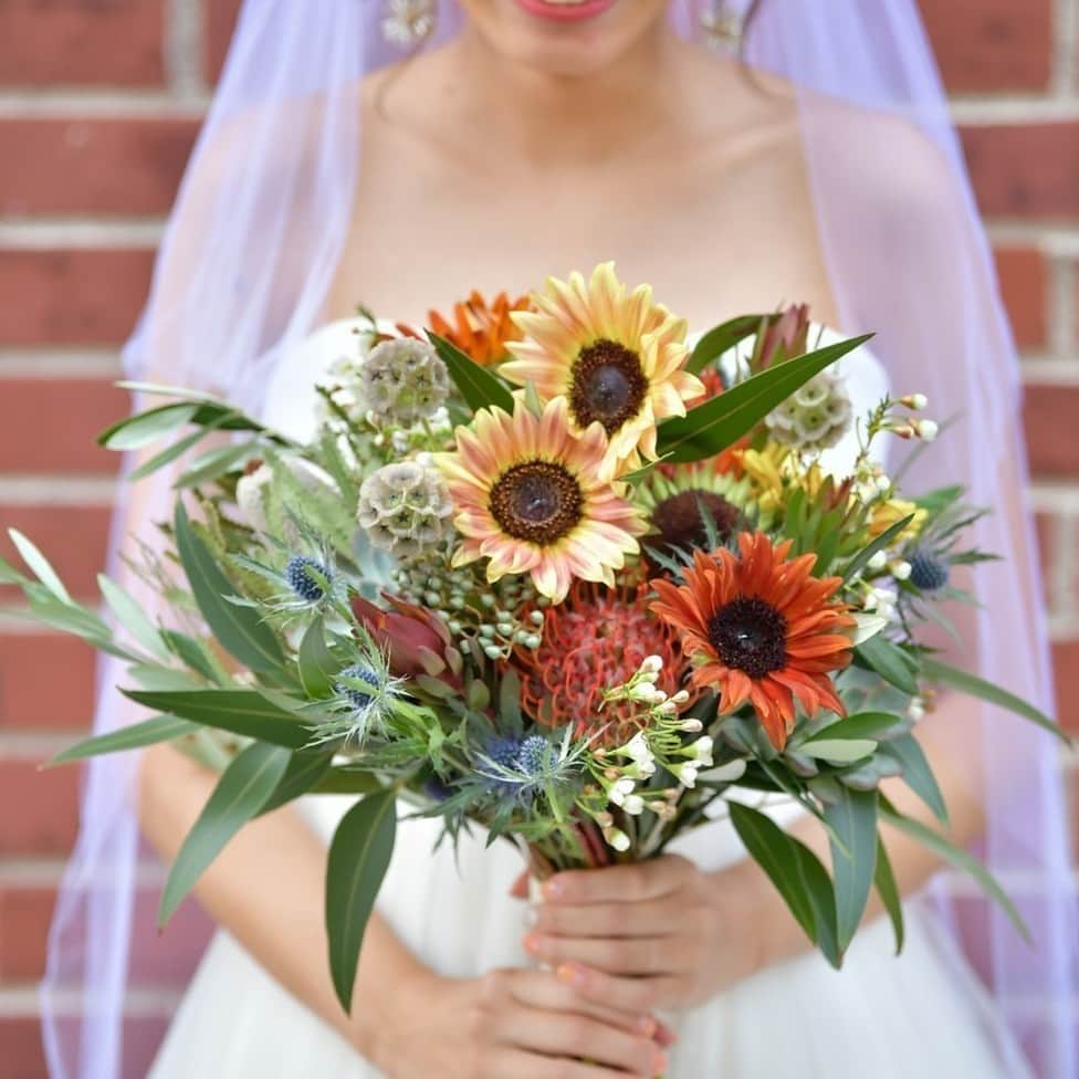 のインスタグラム：「【☀️夏婚花嫁は必見！グラデーションひまわり🌻】﻿ こんばんは！ハナレポ編集部のがみこです🌺﻿ ﻿ 5月に入り、夏婚を控える花嫁さんは結婚式準備が忙しくなってくる時期ではないですか💁‍♀️？﻿ ﻿ 夏婚の先輩花嫁n_weddingさんは、インスタで見つけたグラデーションになっているひまわり（プロカットプラムというらしいです！）をブーケと装花に使っていました🌻🌻🌻﻿ ﻿ —————————————————————﻿ 👰n_weddingさんのハナレポ📝﻿ https://www.weddingpark.net/hanarepo/1422/﻿ —————————————————————﻿ 本日のストーリーズからも飛べます✈️﻿ ﻿ ﻿ もともとひまわりが大好きだというn_weddingさん☺️﻿ でも、普通のひまわりだと会場や自分たちのイメージと合わず、悩んでいたところこのひまわりに出逢ったんだとか💕﻿ ひまわり以外も珍しいお花をふんだんに使っていて、存在感たっぷりです💐﻿ ﻿ //////////////////////////////﻿ #ウエパ と #ハナレポ をつけて﻿ 投稿してください❣️﻿ 素敵な投稿は @weddingpark で﻿ ご紹介させていただきます！﻿ //////////////////////////////﻿ ﻿ #ハナレポ #ウエパ #ウエディングパーク #日本中の卒花嫁さんと繋がりたい #日本中のプレ花嫁さんと繋がりたい #夏婚 #2020夏婚 #2020秋婚 #weddingpark #プレ花嫁準備 #ブーケ #ひまわりブーケ #ひまわり装花 #プロカットプラム #ウェディングブーケオーダー #結婚式ブーケ #クラッチブーケ #baysidegeihinkanveranda」