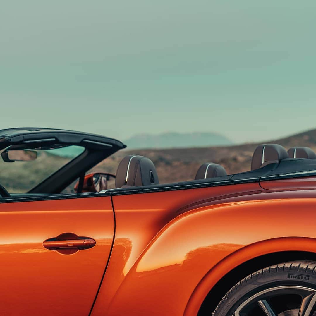 のインスタグラム：「With the roof down, the exterior and interior of the new #ContinentalGTC blend effortlessly together. Exterior paint: Orange Flame. Discover through link in bio.  Continental GT Convertible WLTP drive cycle: fuel consumption, mpg (l/100km) - Combined 20.2 (14.0). Combined CO2 – 317 g/km.」