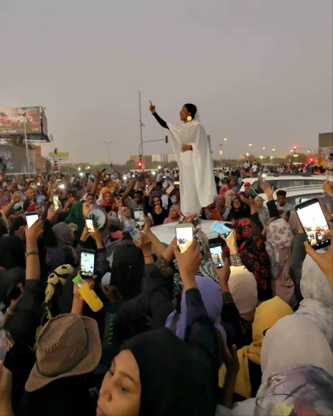 ルモンドさんのインスタグラム写真 - (ルモンドInstagram)「Tout le Soudan connaît désormais la photo de cette jeune femme, prise le 8 avril à Khartoum, alors qu'elle harangue une mer de manifestants depuis le toit d’une voiture, chantant des chansons à la gloire de la « révolution ». Habillée de façon à rappeler les grands mouvements populaires qui ont contribué à jeter à bas deux régimes militaires, en 1964 et 1985, au Soudan, elle incarne celles qu’on appelle les « kandakas ». C’était le titre des reines mères du royaume de Koush, qui a érigé des dizaines de pyramides à trois heures de route au nord de Khartoum, et donné au pays, juste avant l’ère chrétienne, une impératrice qui avait défait les légions romaines d’Auguste. Majoritaires dans les manifestations, ces femmes mènent le mouvement de contestation qui a commencé le 19 décembre 2018, et réclament davantage de place dans la société soudanaise. - Photo : Courtesy Lana H. Haroun (@lana.h.haroun) via Reuters (@reuters) - #Sudan #SudanUprising #Kandakas #SudanRevolt」4月10日 22時35分 - lemondefr