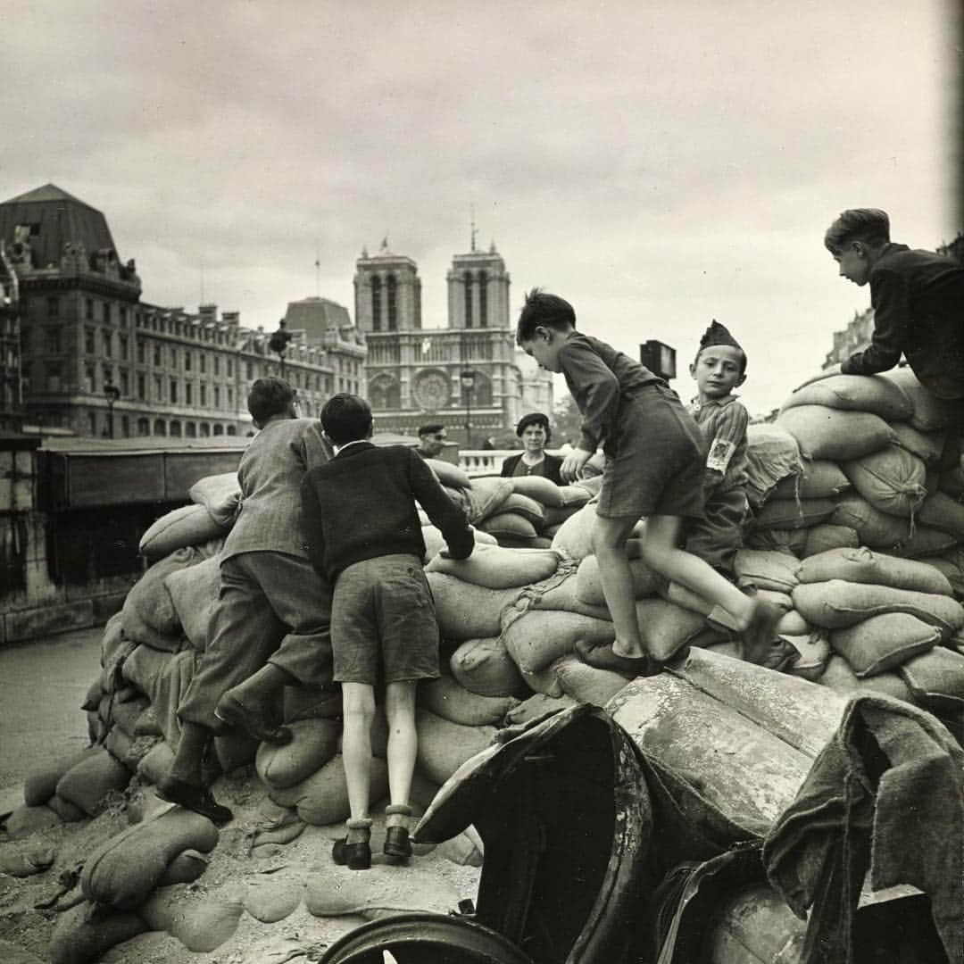 Vogueさんのインスタグラム写真 - (VogueInstagram)「Notre-Dame has been a symbol of the beauty and history of Paris for generations. Today, the iconic spire of the cathedral caught fire and eventually collapsed. Though the cause is still unclear, officials reportedly have said that it could be linked to renovation work on the historic site. Crowds gathered on the streets and bridges of Paris to watch and mourn as around 400 firefighters were deployed to the cathedral to work to contain the flames. Above: Young French boys climbing on barricades of sand bags near Notre-Dame, in Paris, during World War II. Photographed by Lee Miller, Vogue, October 1944」4月16日 6時00分 - voguemagazine