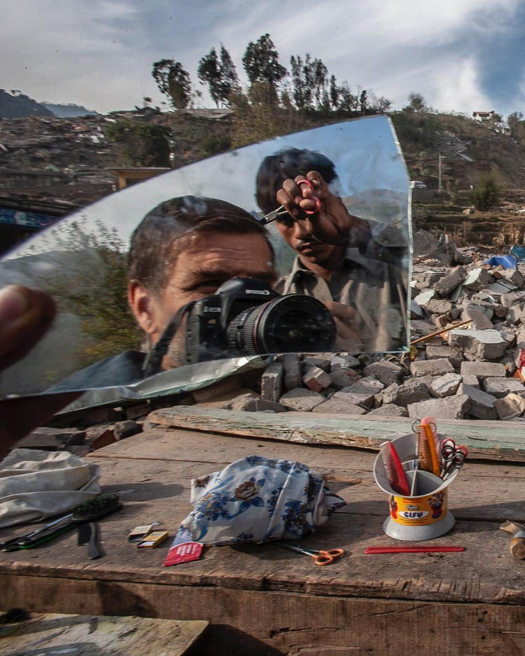 ジョン・スタンメイヤーさんのインスタグラム写真 - (ジョン・スタンメイヤーInstagram)「Swipe - It was October 8, 2005, when the earth did what its always done. That time it was in Pakistan-administered Kashm​ir. ⠀⠀⠀⠀⠀⠀⠀⠀ We’re all only allowed briefly upon the earth. Never owning it. Never able to control anything on our planet, no matter how much we believe or may try. ⠀⠀⠀⠀⠀⠀⠀⠀ Over 50% of Balakot, Patikka, and surrounding areas were destroyed. Estimates put the number of dead at 85,000 but it’s believe to be over 100,000. So many injured or crippled for life. Yet those who survived pushed on. ⠀⠀⠀⠀⠀⠀⠀⠀ There’s this spirit, borne within us, where I’ve seen what can be done. When we no longer see ourselves as different than the other. Race, creed, borders, they no longer exist. Our commonality arrives and we realize…we’re just people. ⠀⠀⠀⠀⠀⠀⠀⠀ Nature has a way of making us humble, right at those moments, when we thought we had it all together. ⠀⠀⠀⠀⠀⠀⠀⠀ Photo 1: I had the best haircut from barber Abdur Rashid in Balakot. All he had left was a shard of his shops mirror, some scissors and a few combs. ⠀⠀⠀⠀⠀⠀⠀⠀ Photo 2: Afternoon prayers at what remained of the mosque in Balakot. ⠀⠀⠀⠀⠀⠀⠀⠀ Photo 3: A mother grieves at the grave of her child who died in the 2005 Kashmir earthquake. ⠀⠀⠀⠀⠀⠀⠀⠀ Photo 4: Bandi Mir Sandani-2 cam​p in Pakistan-controlled Kashm​ir. The camp housed over 350 earthquake survivors in donated tents. ⠀⠀⠀⠀⠀⠀⠀⠀ Photo 5: Those not yet in camps kept warm next to the ruins of their homes in Balakot. ⠀⠀⠀⠀⠀⠀⠀⠀ Photo 6: Moment of happiness when a boy played catch with a watermelon - pinch and zoom on this photo to understand how alive our earth is…much of the mountain is scraped clean of all vegetation. ⠀⠀⠀⠀⠀⠀⠀⠀ Photo 7: After the 7.6 quake destroyed over 50% of Patikka, the only way to cross the Neelum River was over the twisted remains of the bridge. No one ever seemed to give up, no matter how difficult it was. ⠀⠀⠀⠀⠀⠀⠀⠀ Continuing with a series of self portraits with background insight from various assignments over the years with National Geographic, Time magazine and other publications. There’s a reason. More soon. - @viiphoto #pakistan #kashmir #earthquake #destruction #selfportrait #selfie #rareselfie #fromtheotherside」4月17日 13時11分 - johnstanmeyer