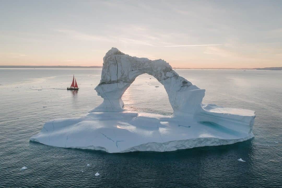 National Geographic Travelさんのインスタグラム写真 - (National Geographic TravelInstagram)「Photo by @kiliiiyuyan | A large iceberg with an arch become a temporary tourist attraction in the Ilulissat ice fjord, a UNESCO World Heritage Site. The red sailboat seen here belongs to a local guide and adds visual interest to tourist photographs. Follow me, @kiliiiyuyan, for more from the Arctic and beyond. #iceberg #greenland #ilulissa」4月23日 16時02分 - natgeotravel
