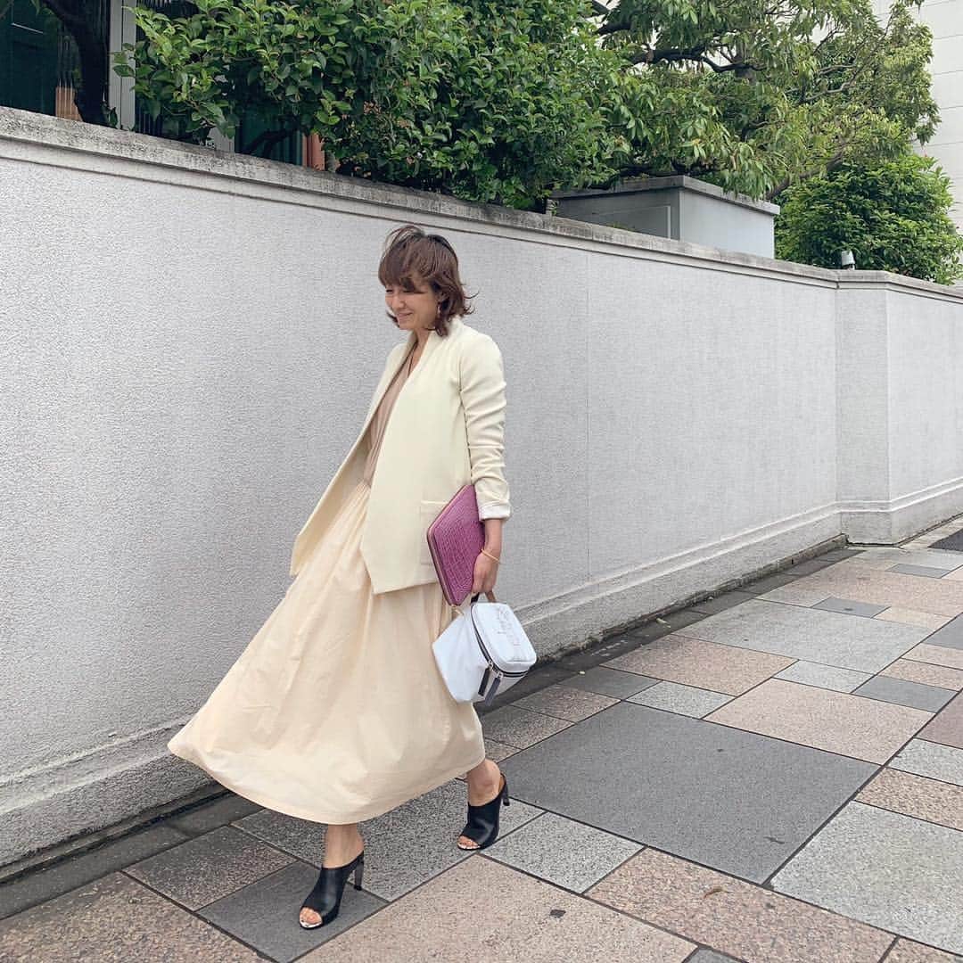 風間ゆみえのインスタグラム：「風がスカートを膨らませたり、揺らしたりするのが好きです。  薄曇りの今日は、くすみをはらうような 柔らかなトーンの服を選んでコーディネート。  靴やバッグの小物は、ぼんやりとし過ぎないように、白、黒、のモノトーンで引き締めて。黒いサンダルはロベールクレジュリー。  @plan_c_official  ピンクベージュの深いVあきのニット、 デザイナーの子供たちが描いた絵がプリントされたボックス型のバッグ  @la_marine_francaise_official  淡いオレンジシャーベットみたいな色のコットンスカート  @roseannaofficiel  シルエットはタイトめでシャープなウールジャケット  @la_boutique_fantasque  バイイングして、入荷を楽しみにしていたピアスは、イエローとピンクのきれいな色の天然石が左右アシンメトリーにデザインされているの。アシンメトリーなものって、とても魅力的に見えるの  @smythson  手に持ったピンク色の型押しの手帳はロンドンの空港でお買い物したもの」