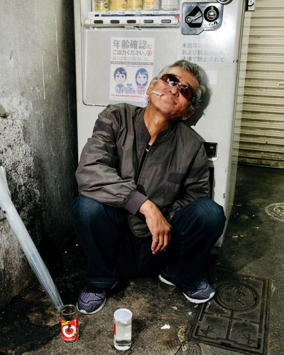 Q. Sakamakiさんのインスタグラム写真 - (Q. SakamakiInstagram)「Kamagasaki Portrait Series: Ken Takakura, 68, dubbing so or Japan's famous ex_actor name by himself poses next to a sake vendor machine. Kamagasaki, Osaka, March in 2019. Kamagasaki is often called as the worst slum and/ or the most dangerous place in Japan. Yet many of them are so friendly and naive. So this time for many images, I have taken so at least somehow. However, it is true that many of Kamagasaki residents love the drinking so much and often tend to take the street fighting. Also there is an open secret — many residents, so many of them retirees, who live in poverty, are often exploited in their welfare system, even jobs, by middle-men, local government’s corruptions and/ or Yakuza, Japanese mafia. So, in addition to the friendly images, I will show Kamagasaki in the so-called typical reportage style as well. #kamagasaki #qs_kamagasaki #osaka #japan」4月26日 21時49分 - qsakamaki
