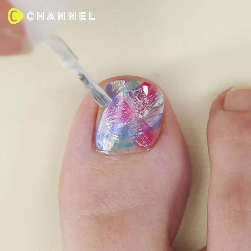 のインスタグラム：「👡セルフで簡単！フェザー風フットネイル💖 . 💗Check👉 @cchannel_girls 🎶 💗Follow me👉 @cchannel_beauty 🎵 . 💄C CHANNELのアプリもよろしくお願いします😊 . そろそろサンダルも活躍してくる季節。  足元のおしゃれ、気にしてますか？？ サンダルから見える爪先も、セルフで可愛く仕上げられるんです♡ . マニキュアの筆で、サッと羽のように  色付けていくだけで、あっというまにカラフルで  おしゃれなペディキュアの完成！ . 【手順】  １：マニキュアのはけ跡がのこるように、しろ、ピンク、青などのマニキュアを塗る  このとき、カーブを描くようにすると綺麗になる  ２：色のバランスを見ながら、色を重ねていく  色で埋め尽くさずに、クリアの部分を残しながら色付けする  ３：重ねが完成したら、根元にトップコートをつけて、スタッズを扇型に並べる  ４：スタッズの真ん中にオーロラのストーンを置く  ５：はみ出たマニキュアをリムーバーで取り除く  ６：トップコートを塗って完成 . produced by esNAIL @esnail_japan . . #サマーネイル#うるつやネイル#フェザーネイル#マニキュアネイル#ポリッシュ派#手元コーデ#綺麗めネイル#自爪ネイル#ショートネイル#フットネイル#ハンドネイル#パラドゥネイル部#手描きアート#エレガントネイル#大人上品#大人綺麗#週末ネイル#ペディキュア#夏コーデ#オーロラネイル#ズボラ女子#カラフルネイル#夏カラー#サンダルコーデ#クリアネイル#つやつやネイル#100均ネイル#ダイソーネイル#スタッズネイル」